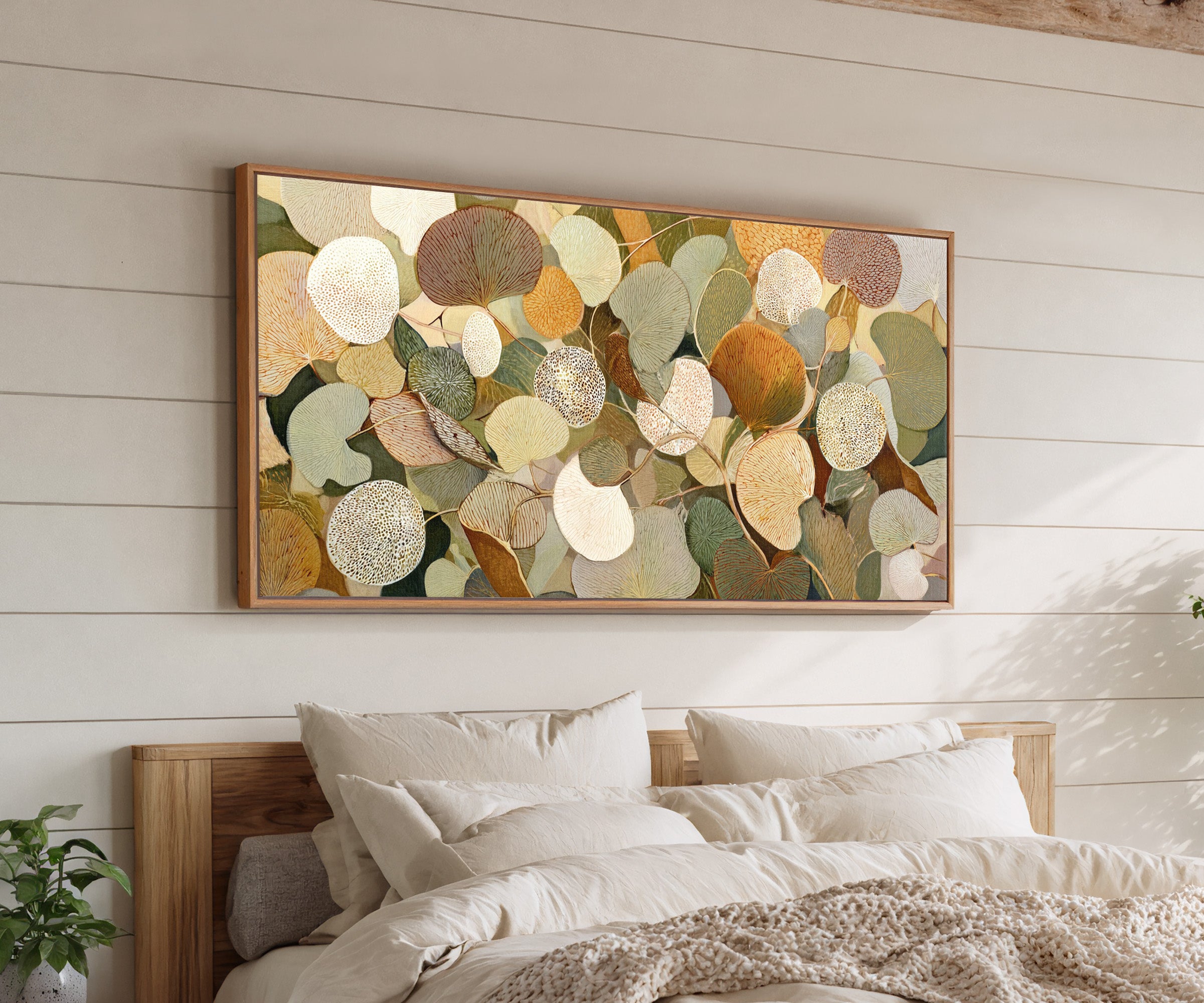 rounded leaf forms in olive, cream, gold, rust, canvas wall art in an oak frame above a bed