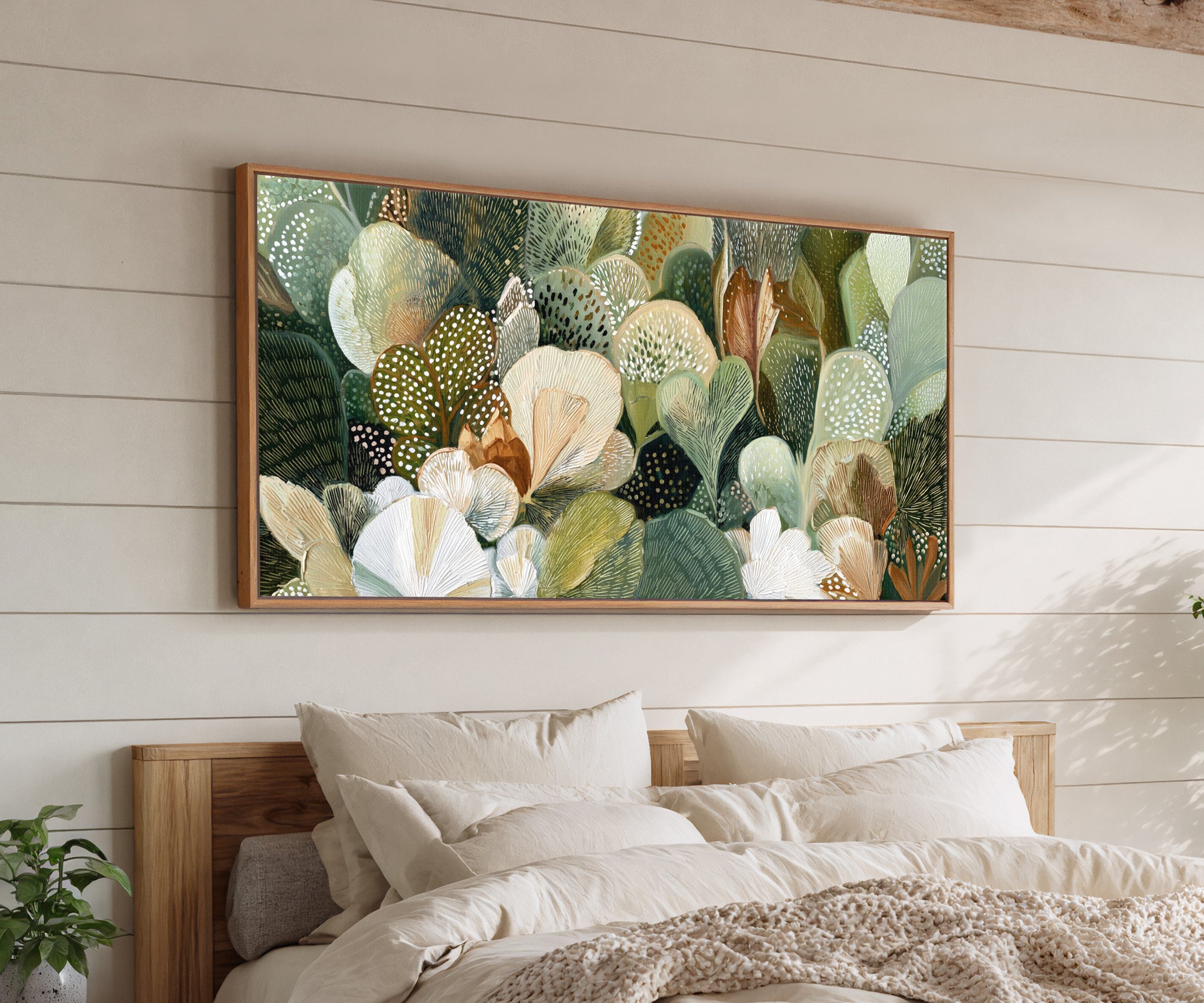 dense green and cream leaf forms canvas wall art in an oak frame above a bed