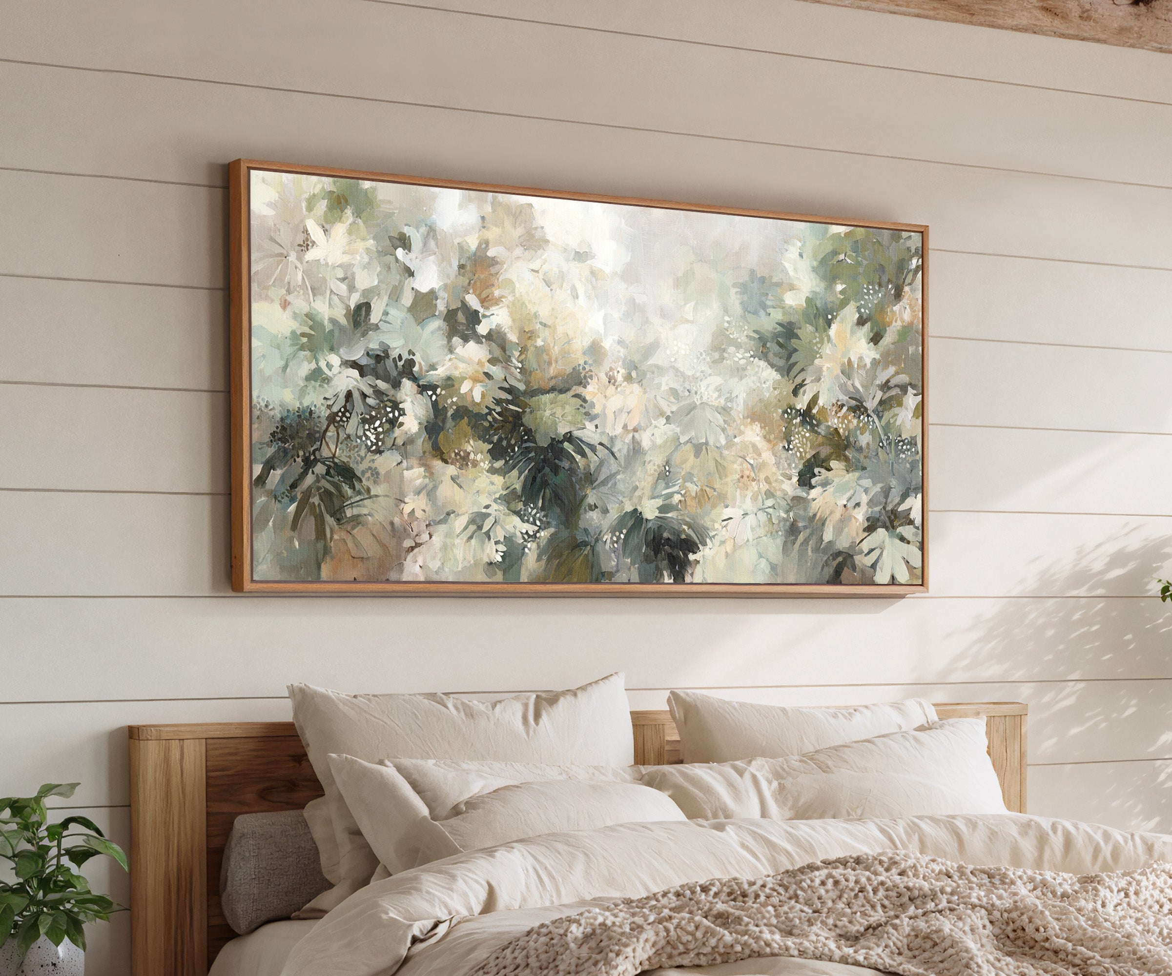 soft layered foliage in cream, sage, olive, and canvas wall art in an oak frame above a bed