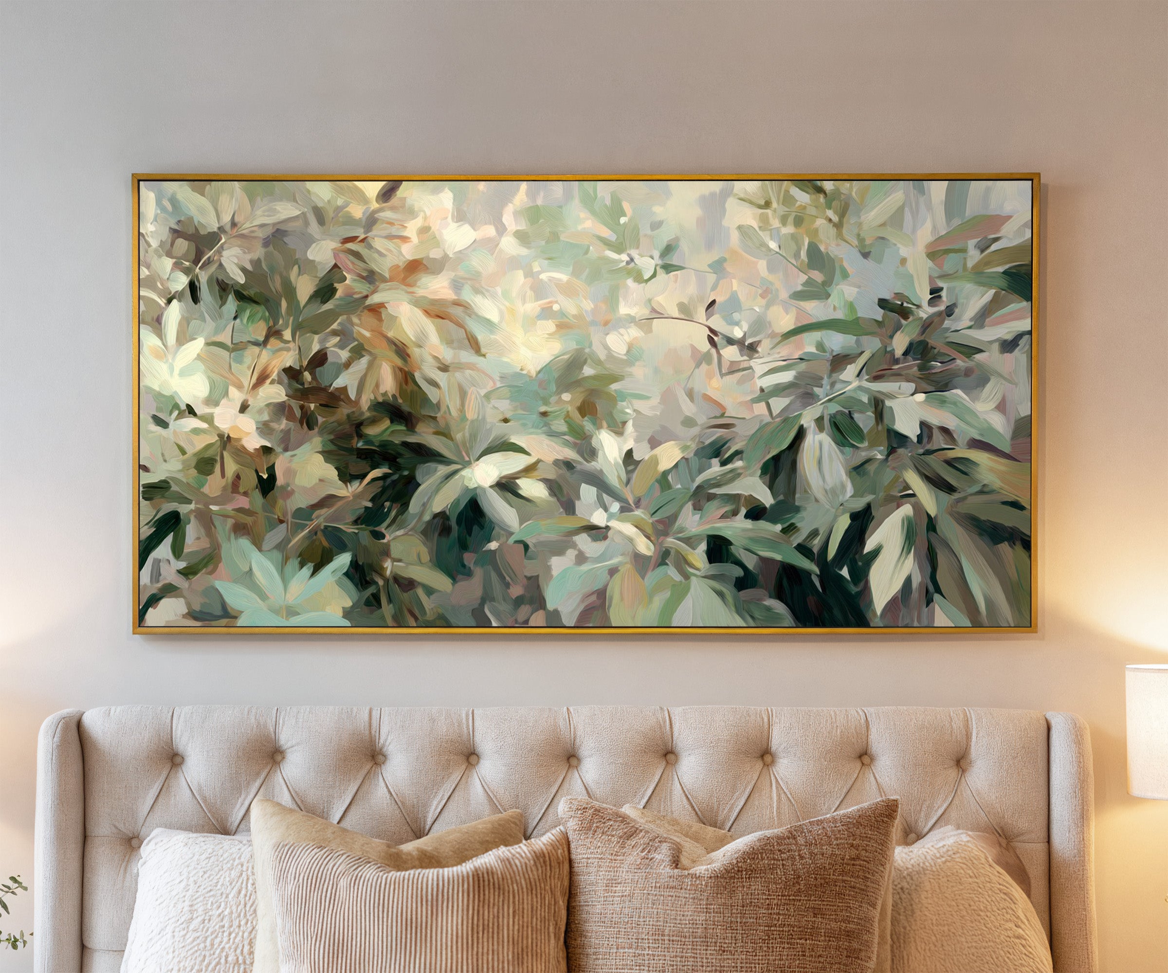 lush layered foliage in soft green, cream, and canvas wall art in a gold frame above a bed