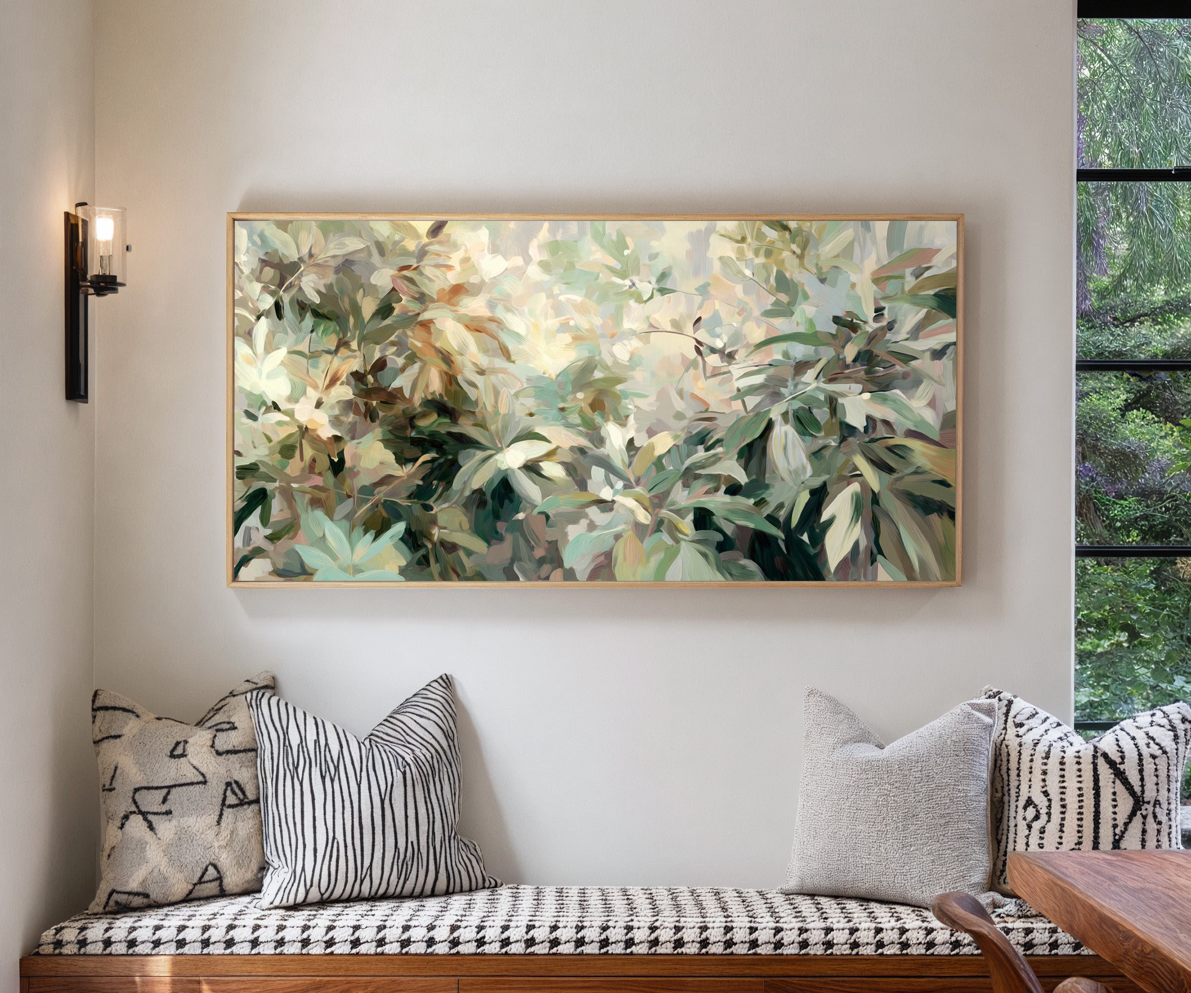 lush layered foliage in soft green, cream, and canvas wall art in a natural wood frame in a living room