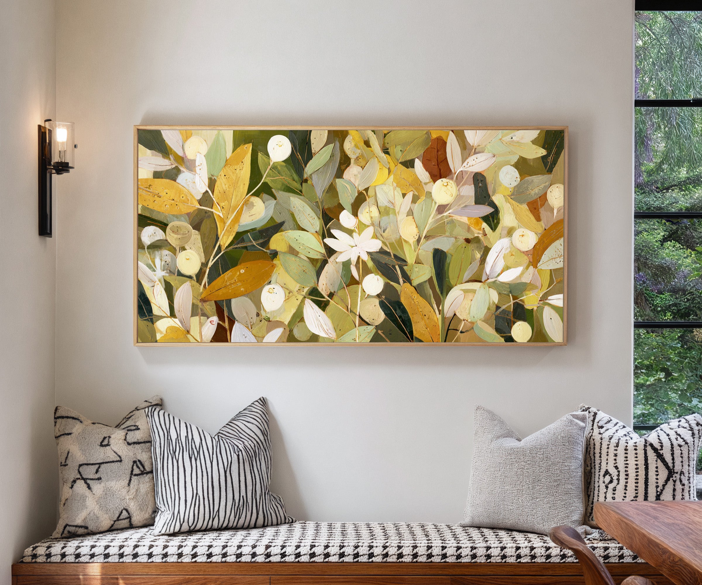 dense olive and gold leaf forms with pale canvas wall art in a natural wood frame in a living room
