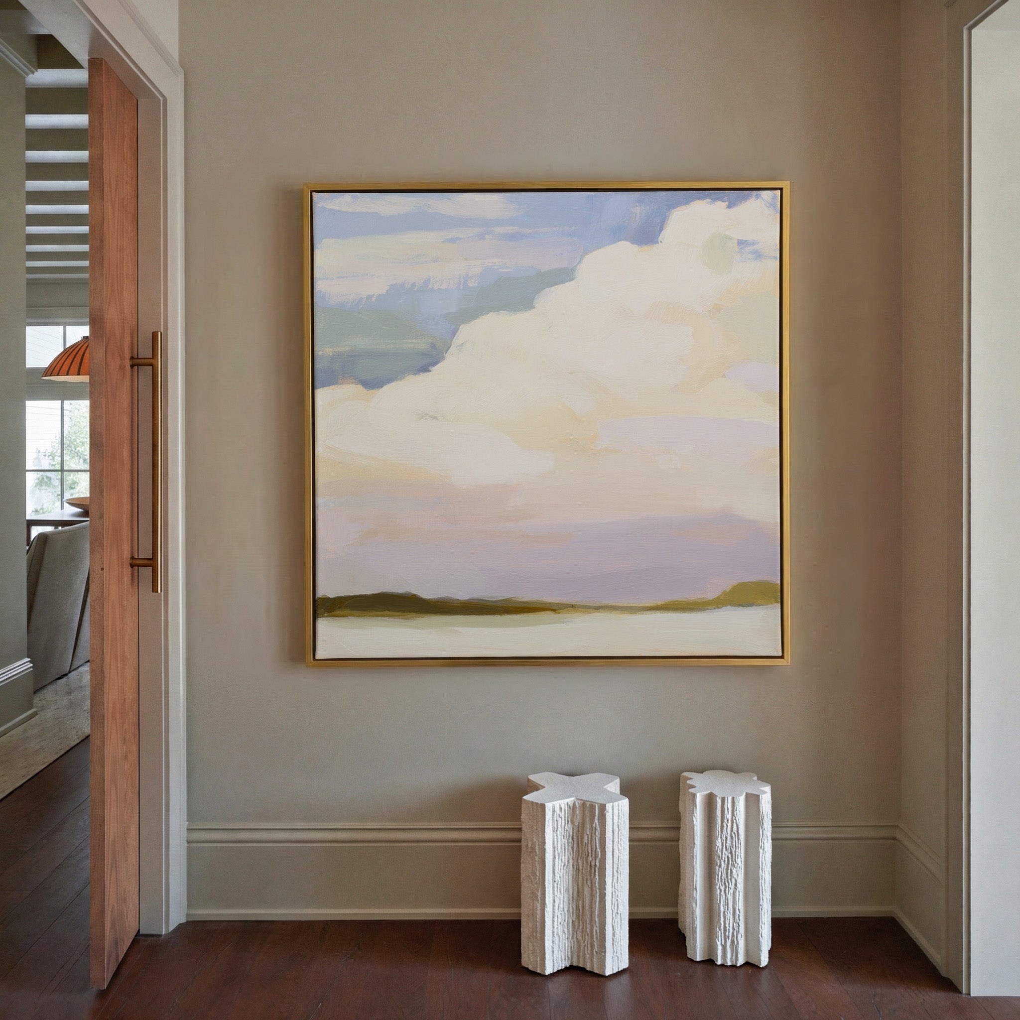 soft white clouds over pale blue and lavender canvas wall art in a gold frame in a styled room setting