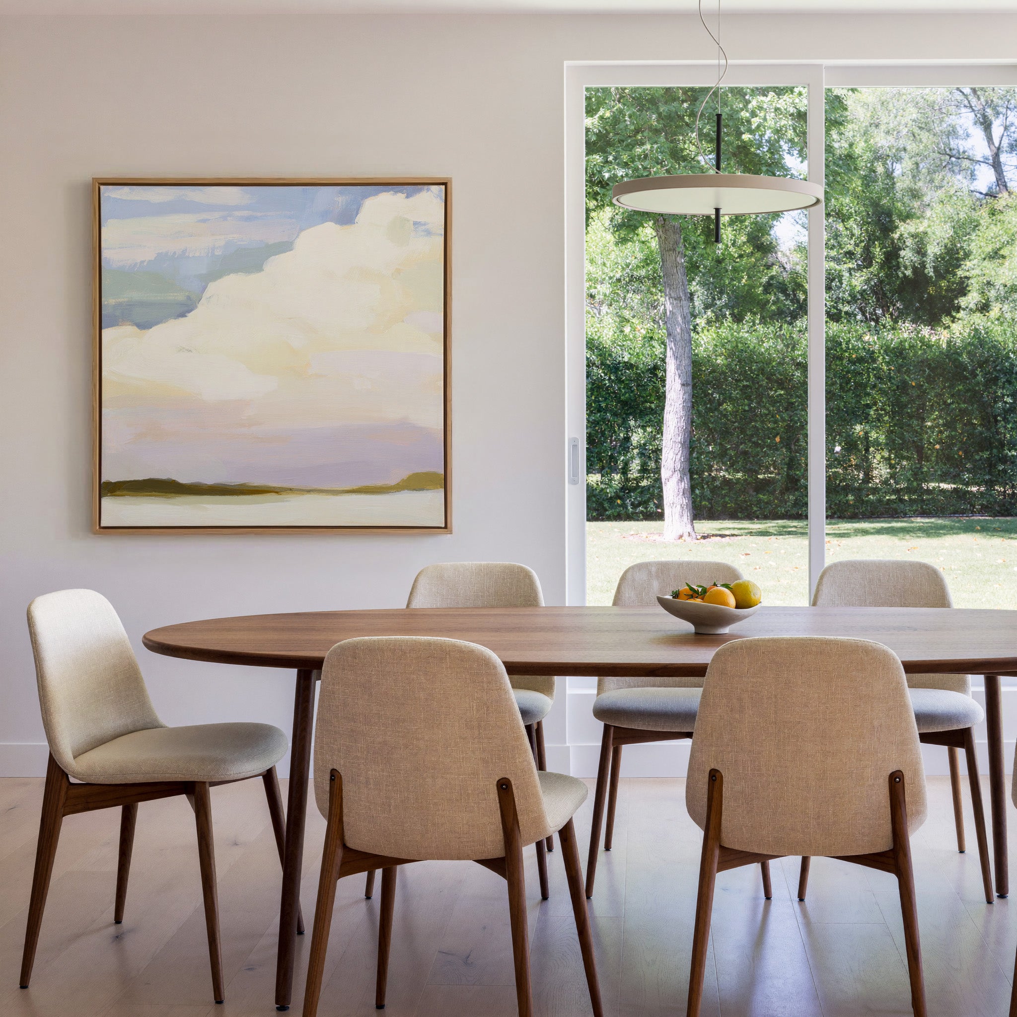 soft white clouds over pale blue and lavender canvas wall art in an oak frame in a dining room
