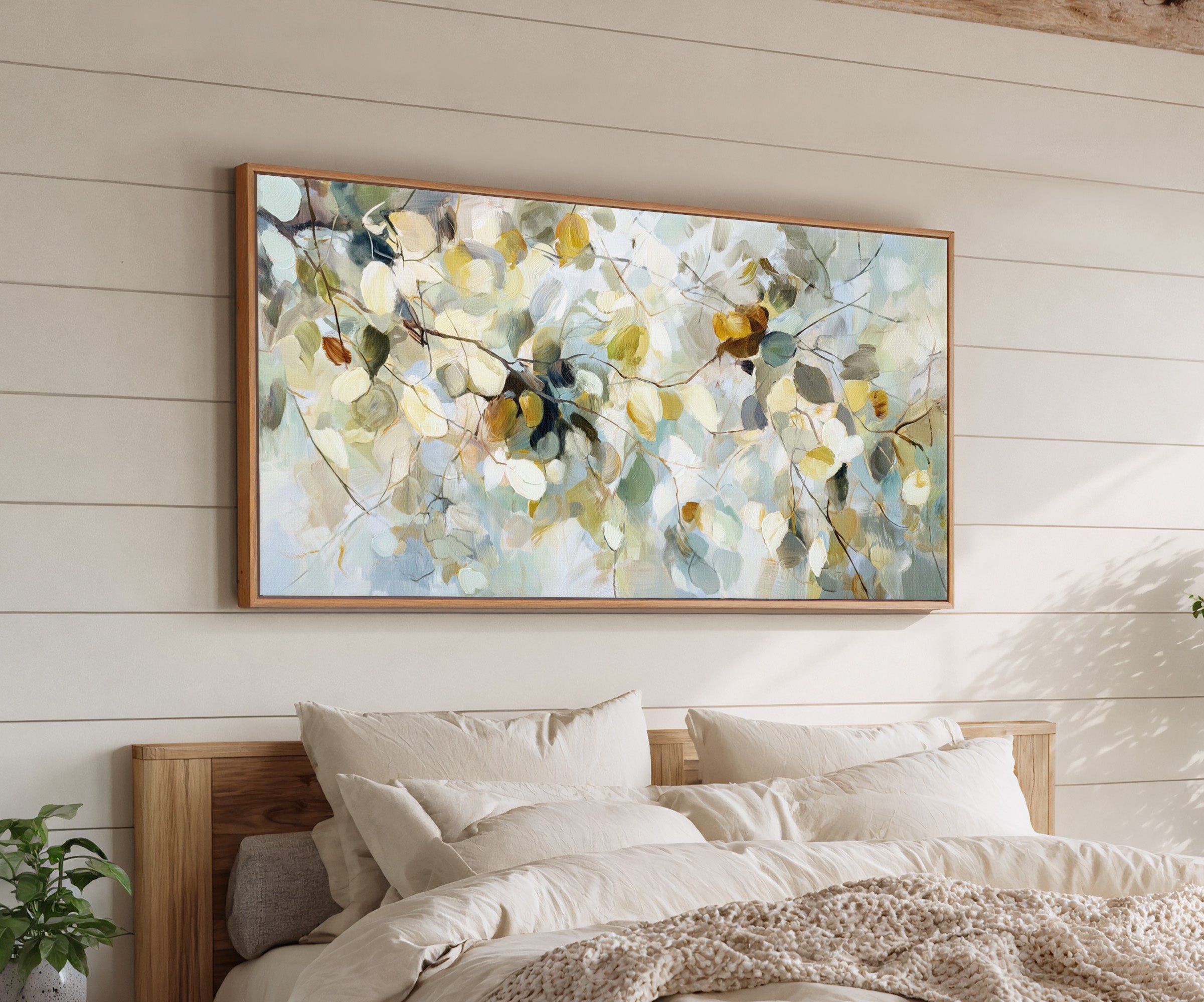 soft blue, cream, and gold leaf branch canvas wall art in an oak frame above a bed