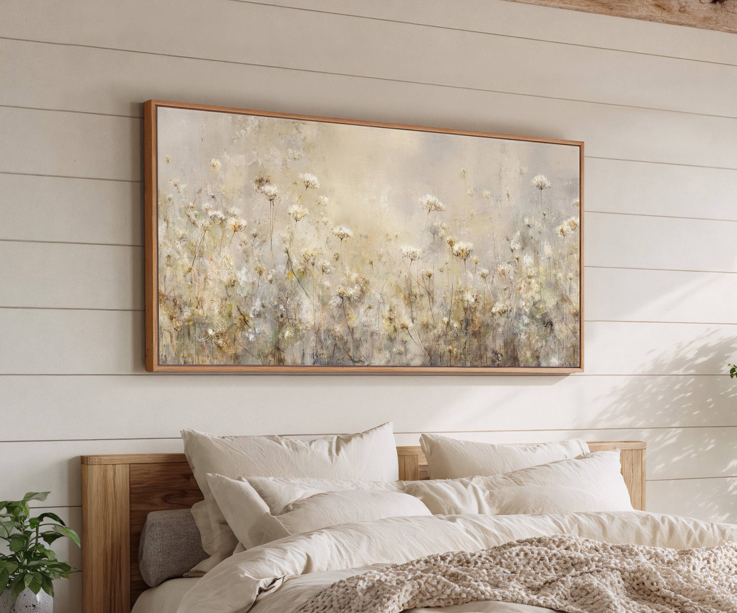 pale wildflower meadow with tall stems and soft canvas wall art in an oak frame above a bed