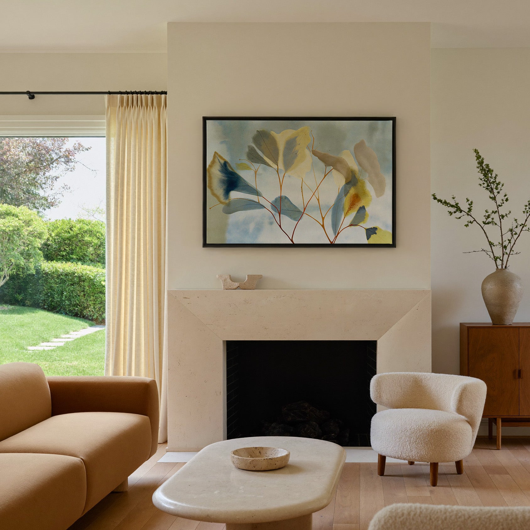 blue, cream, and yellow leaf branch canvas wall art in a black frame above a mantel