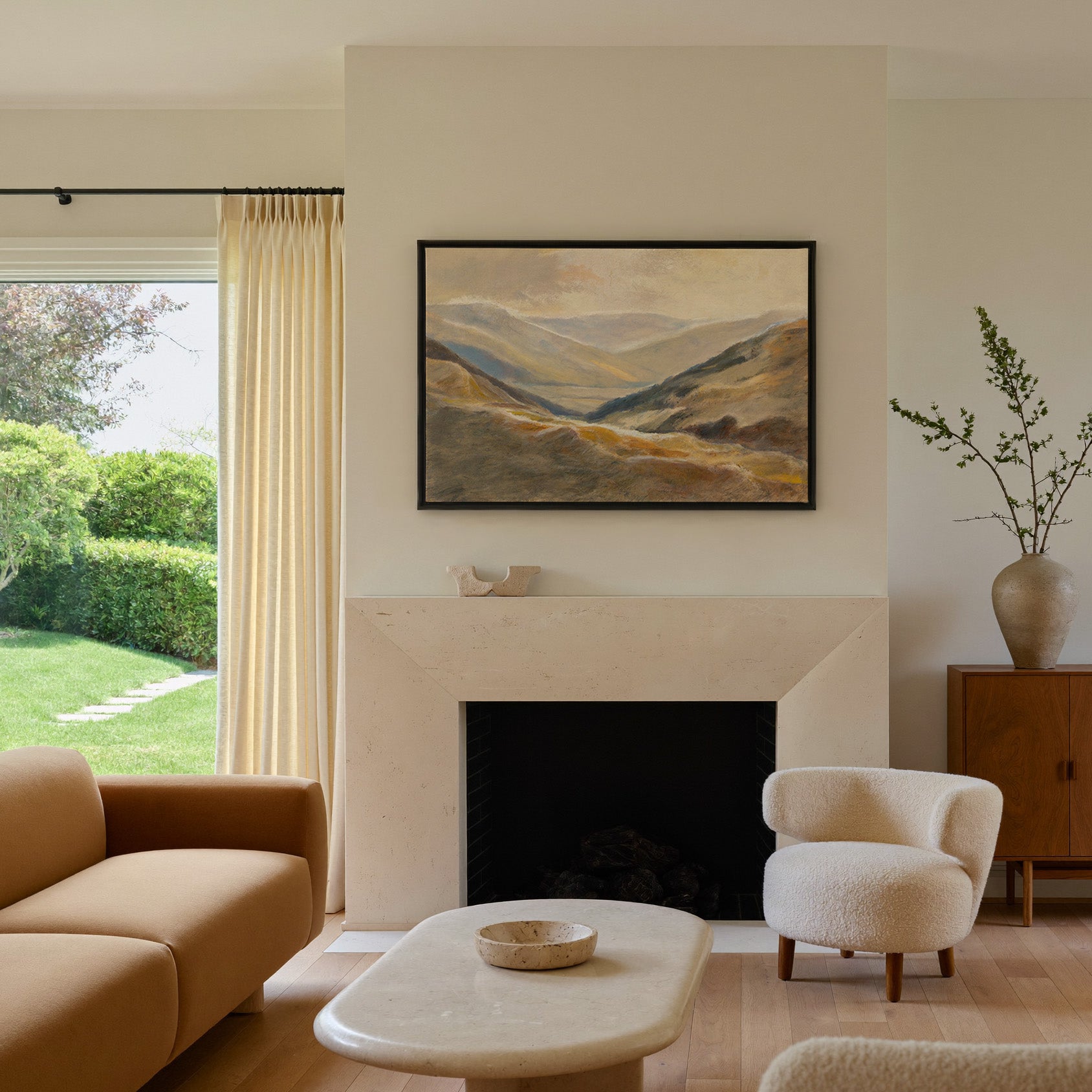 soft beige and blue mountain landscape canvas wall art in a black frame above a mantel