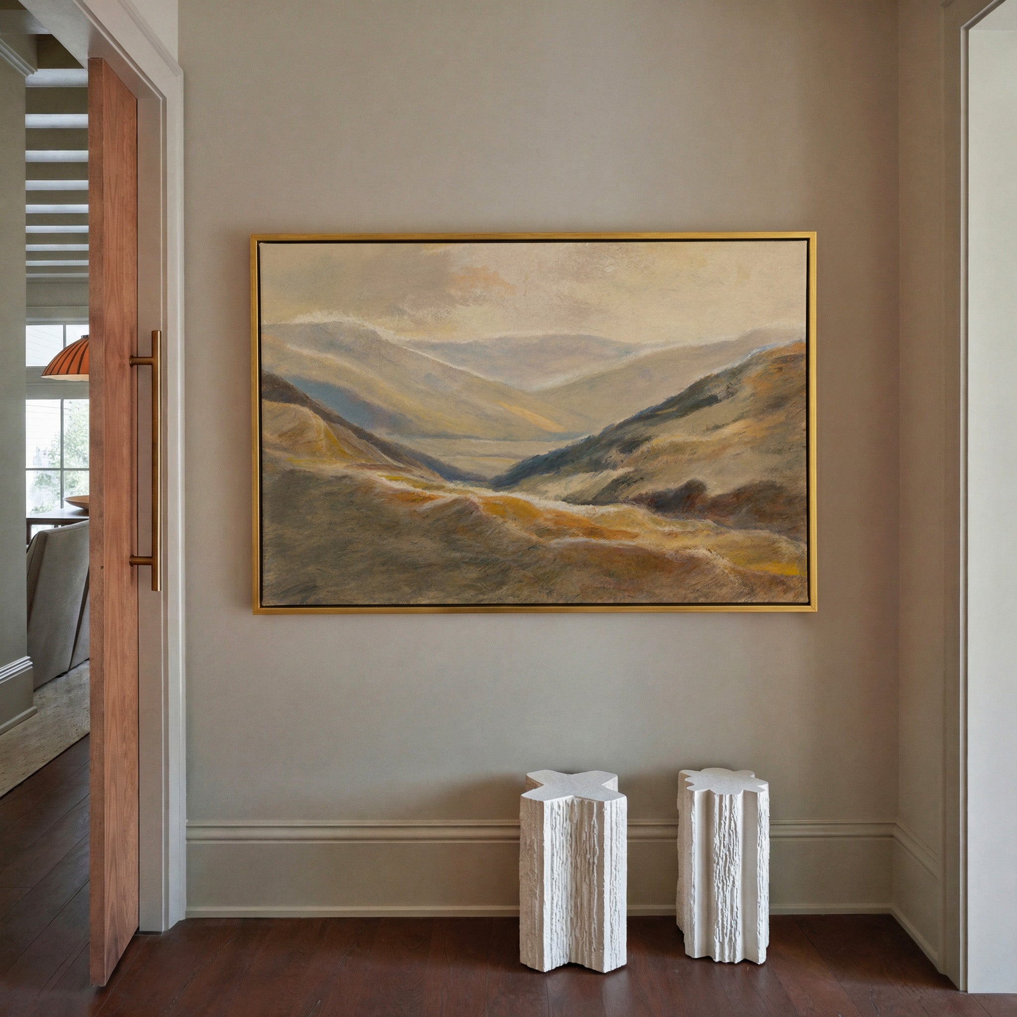 soft beige and blue mountain landscape canvas wall art in a gold frame in a styled room setting