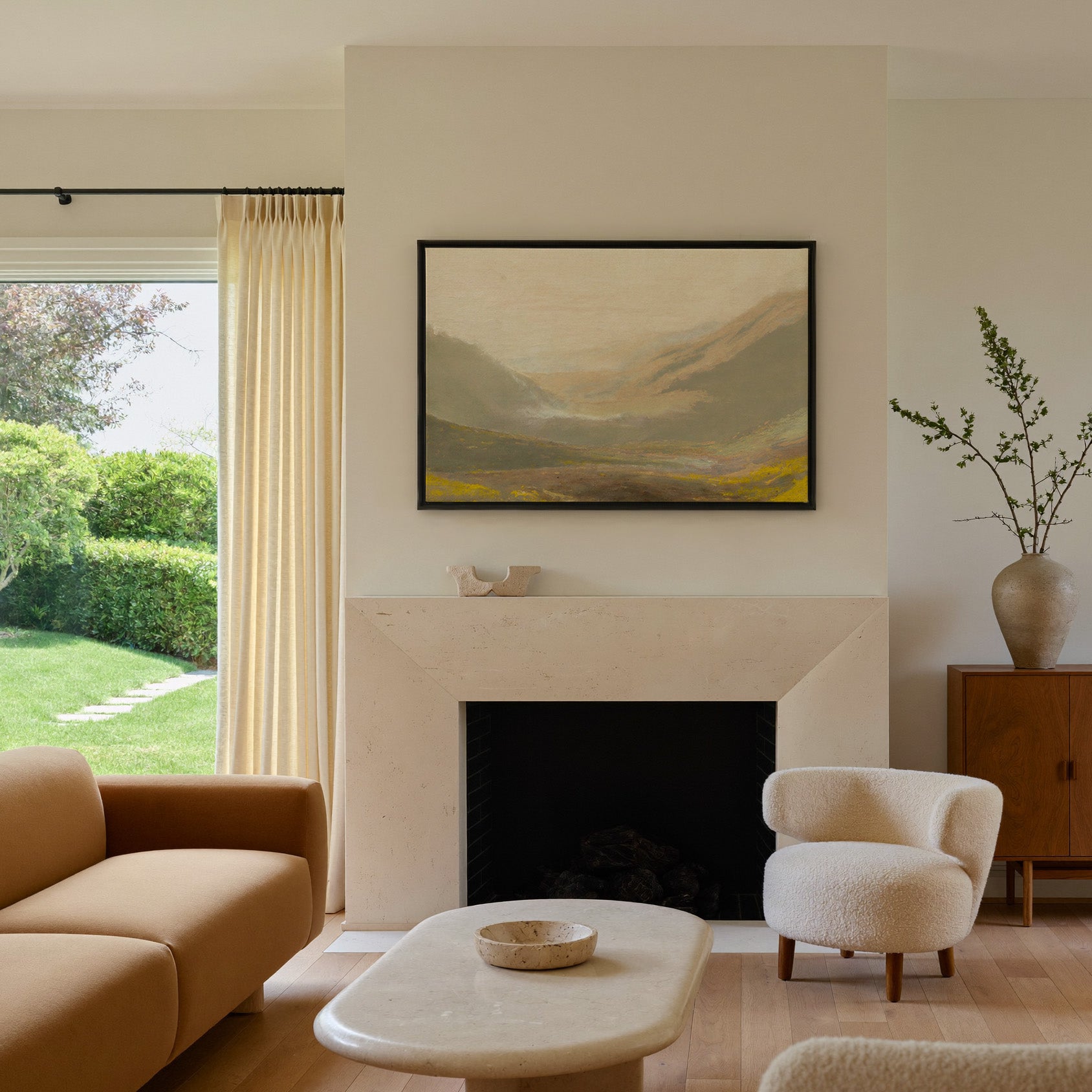 misty valley landscape with ochre hills and a canvas wall art in a black frame above a mantel