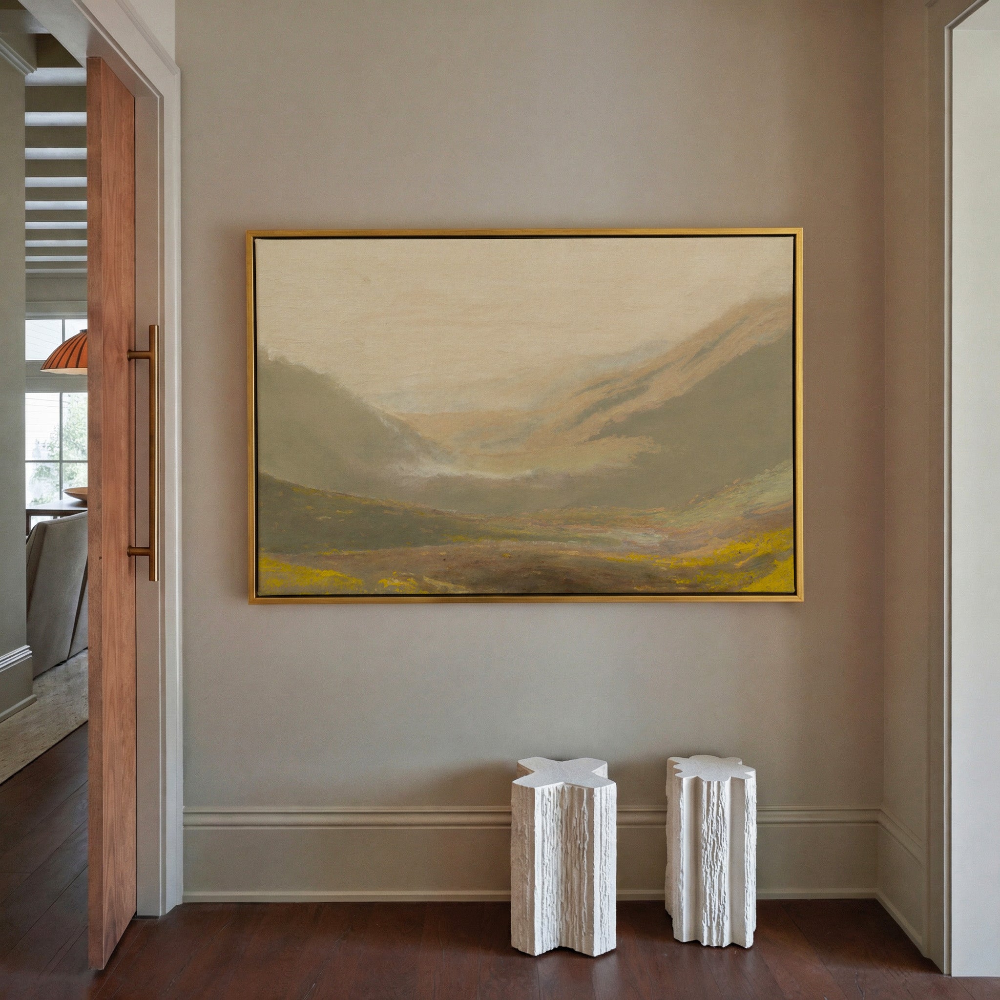 misty valley landscape with ochre hills and a canvas wall art in a gold frame in a styled room setting