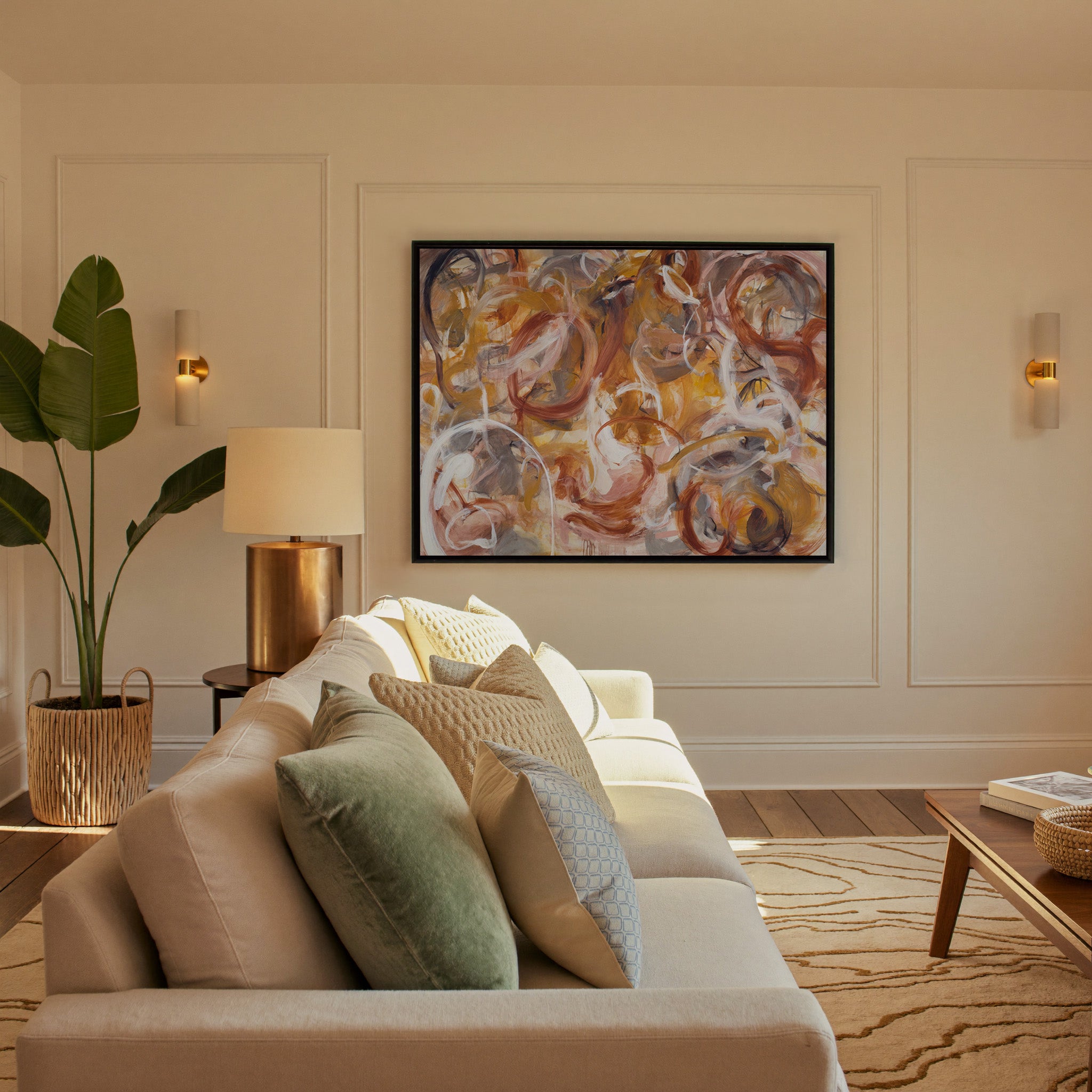 warm rust, gold, cream, and gray abstract with canvas wall art in a black frame in a styled room setting