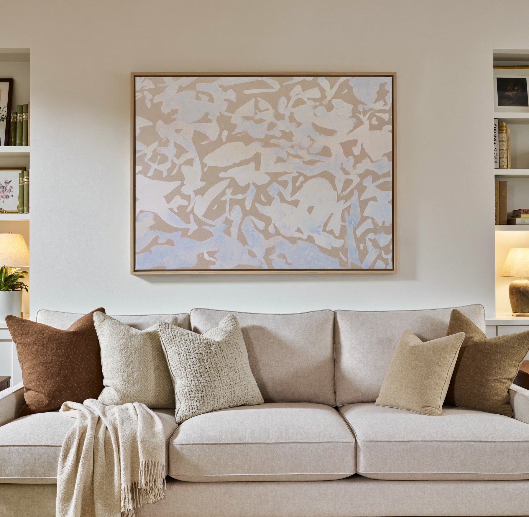soft beige and pale blue abstract canvas wall art in a natural wood frame in a styled room setting