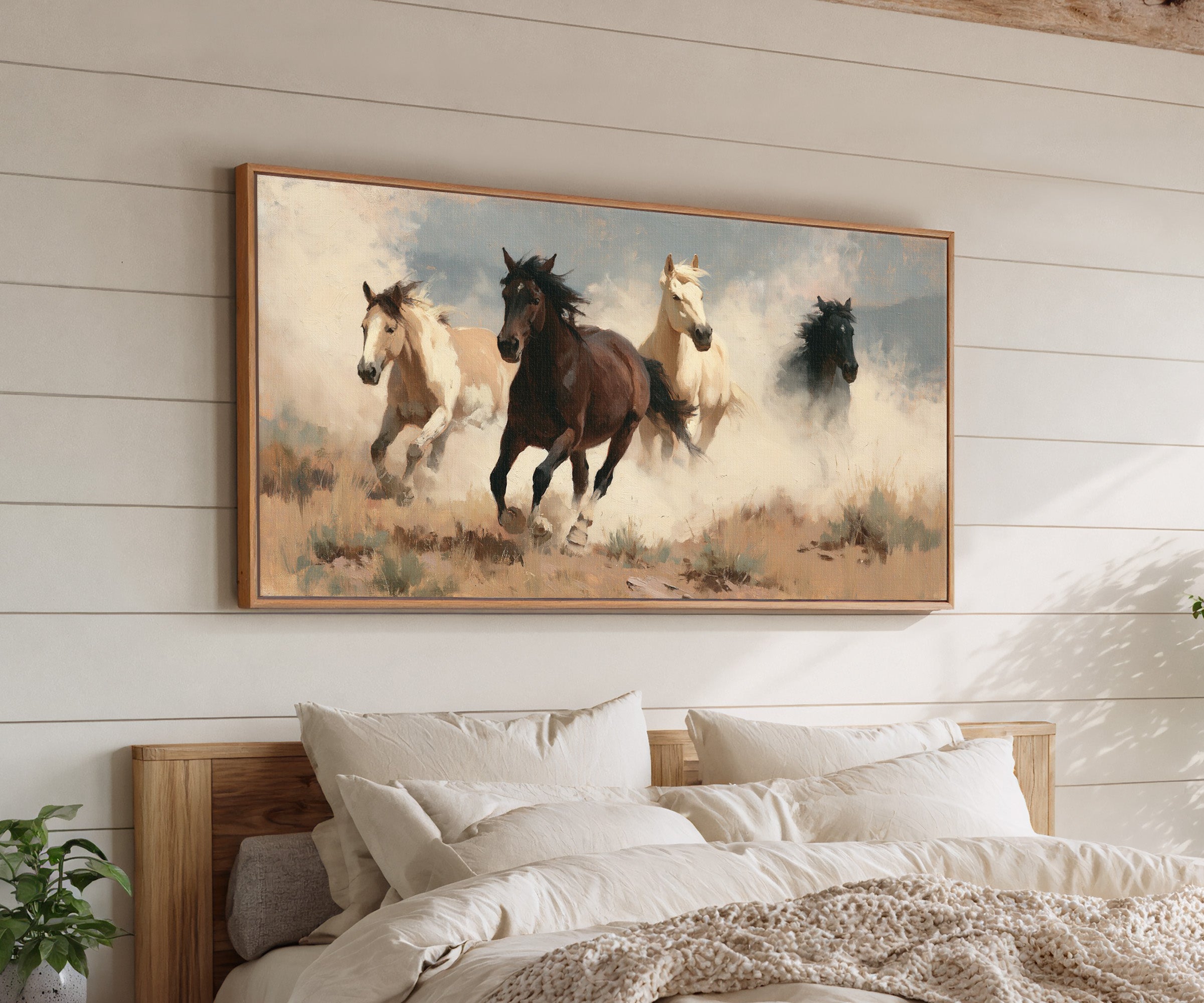 running horses in a dry open field with dust canvas wall art in an oak frame above a bed