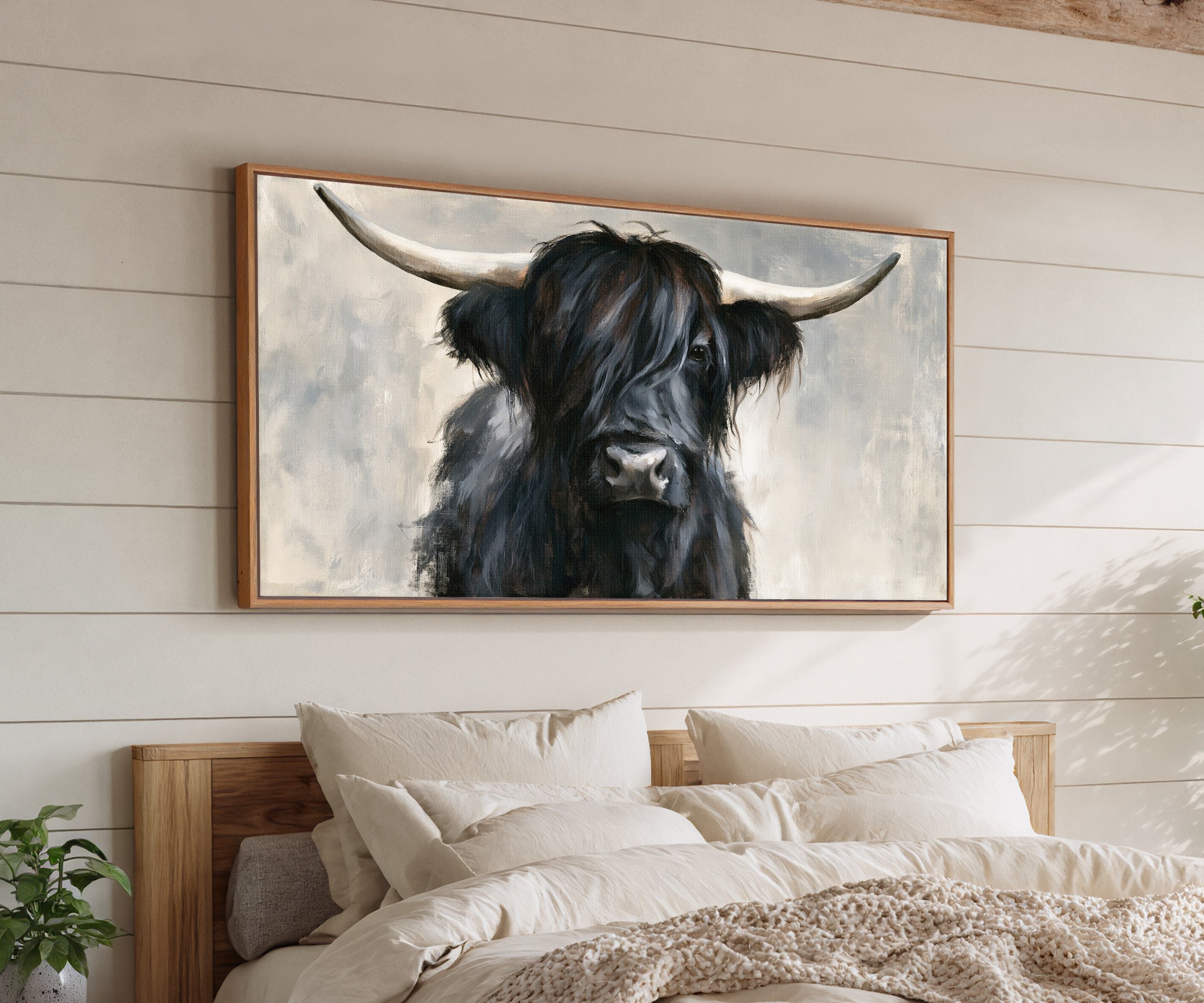 black highland cow with long shaggy hair and canvas wall art in an oak frame above a bed