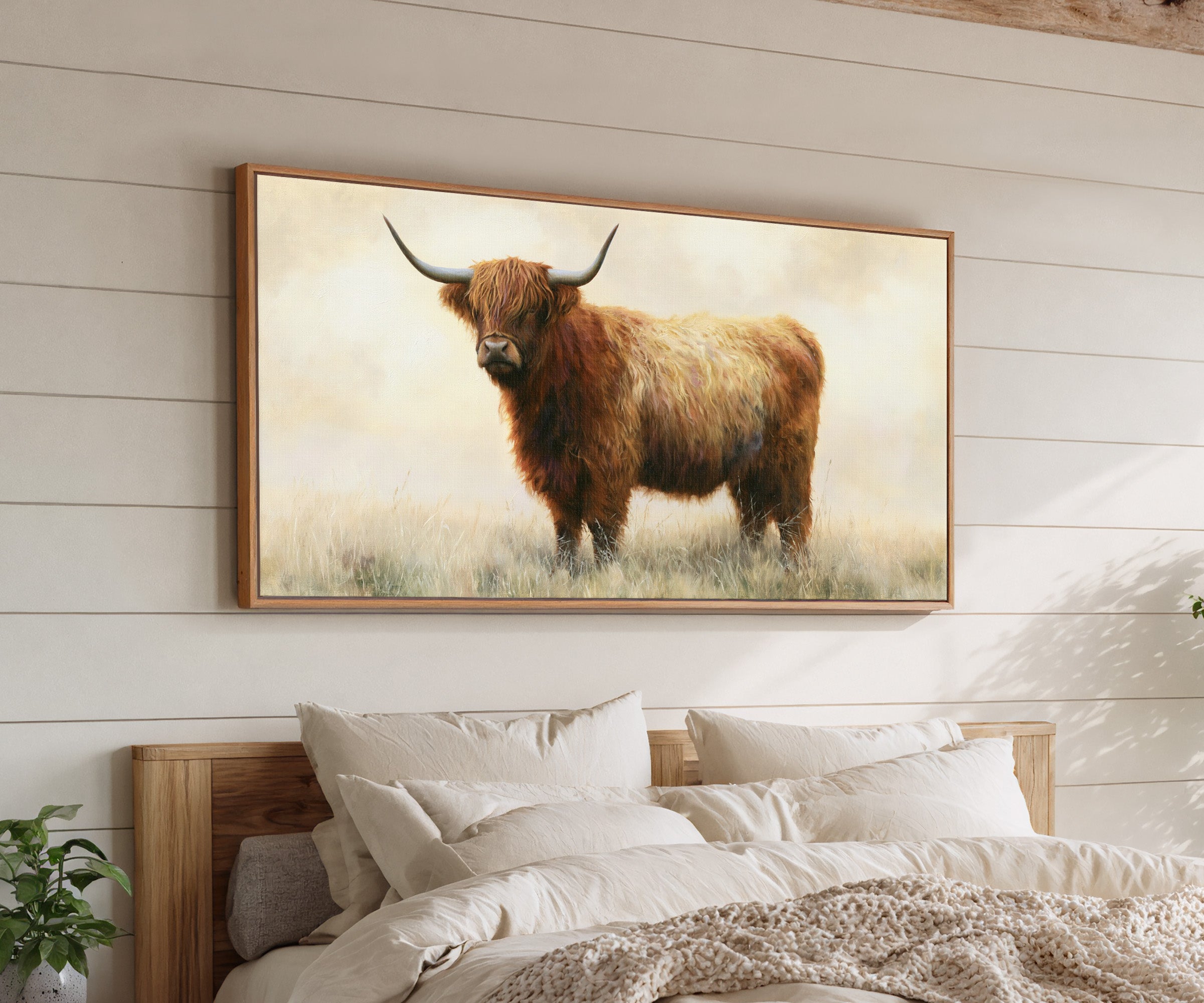 warm brown highland cow in pale dry grass canvas wall art in an oak frame above a bed