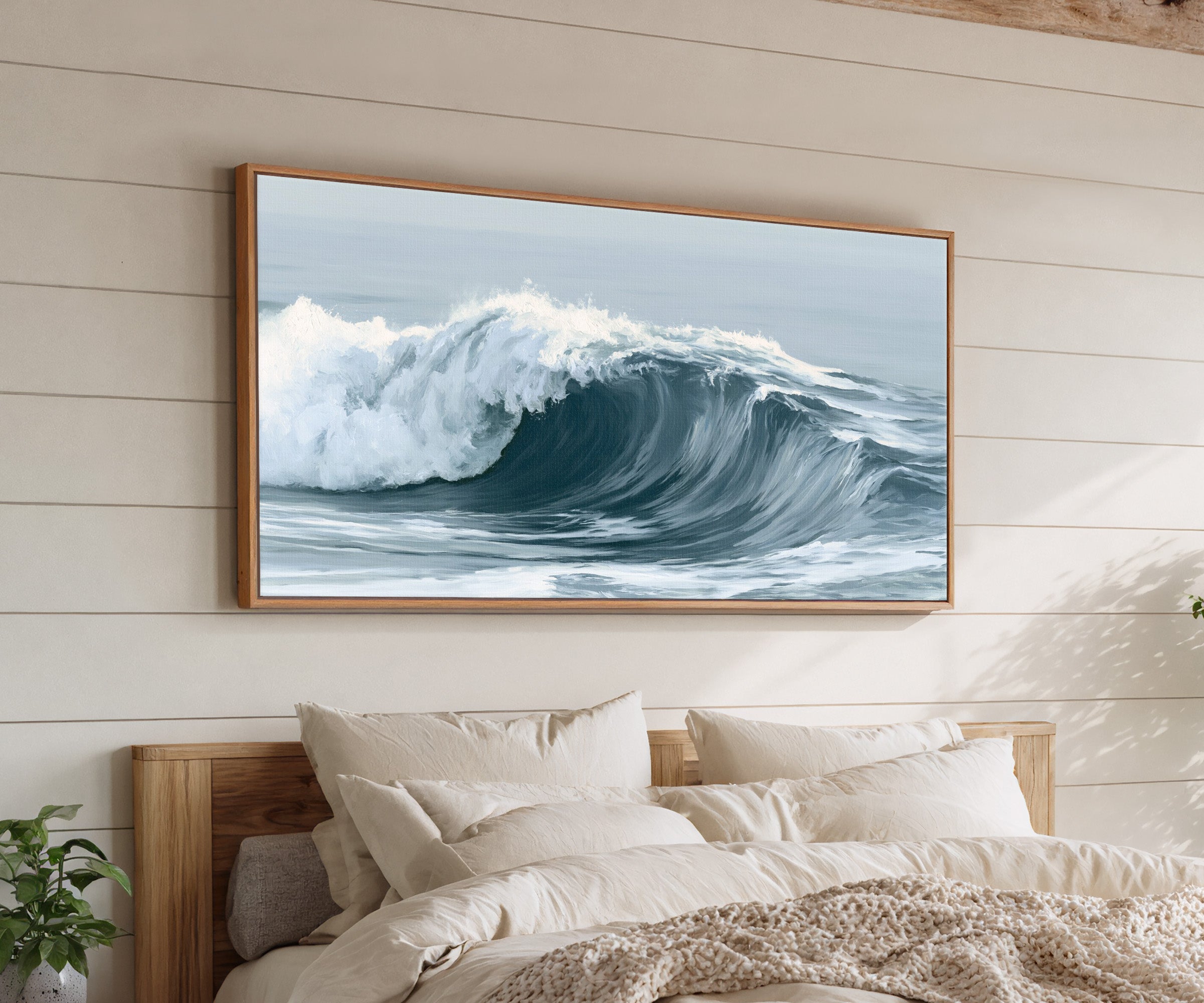deep muted blue ocean wave canvas wall art in an oak frame above a bed