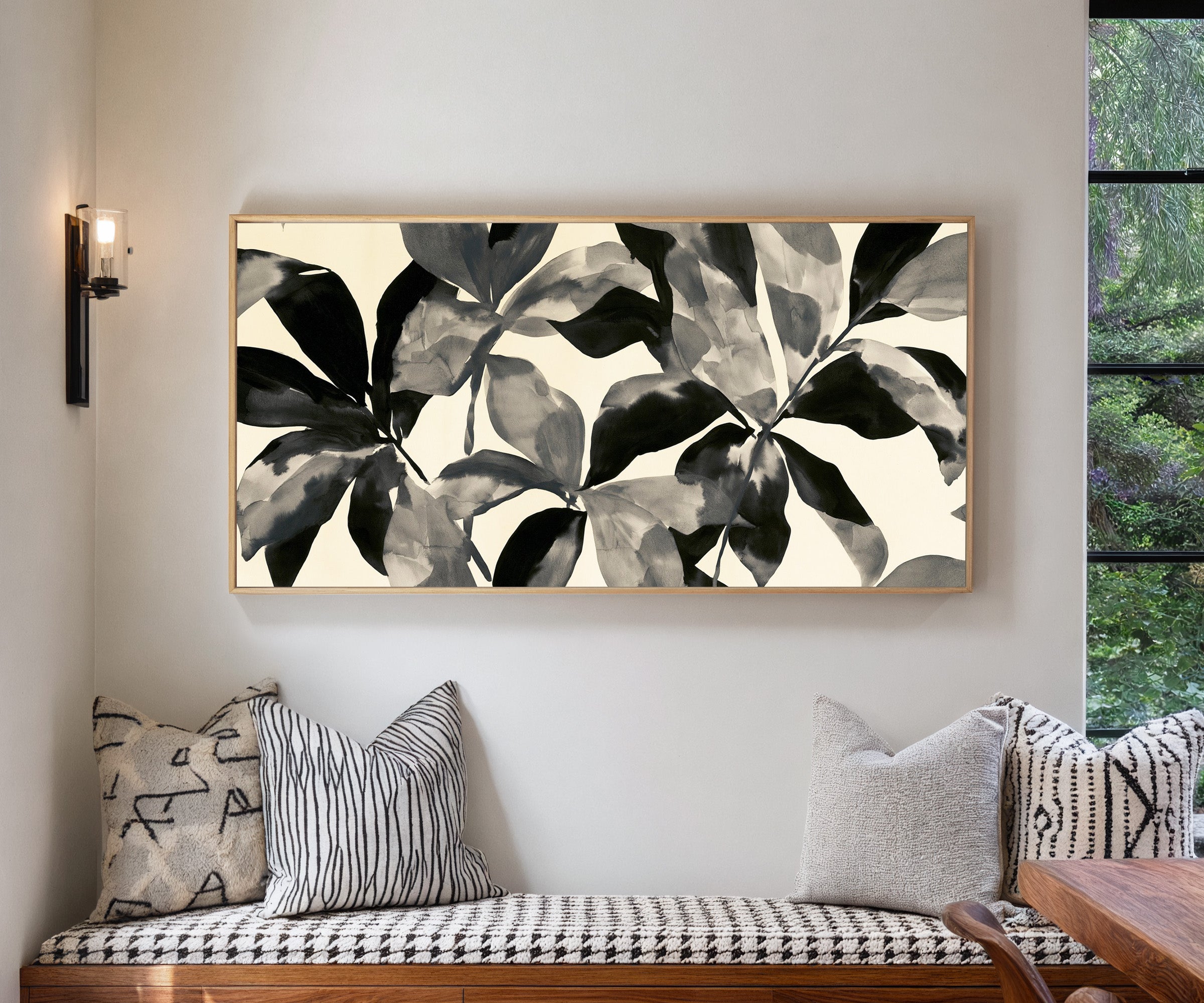 overlapping black and gray leaf shapes on cream canvas wall art in a natural wood frame in a living room
