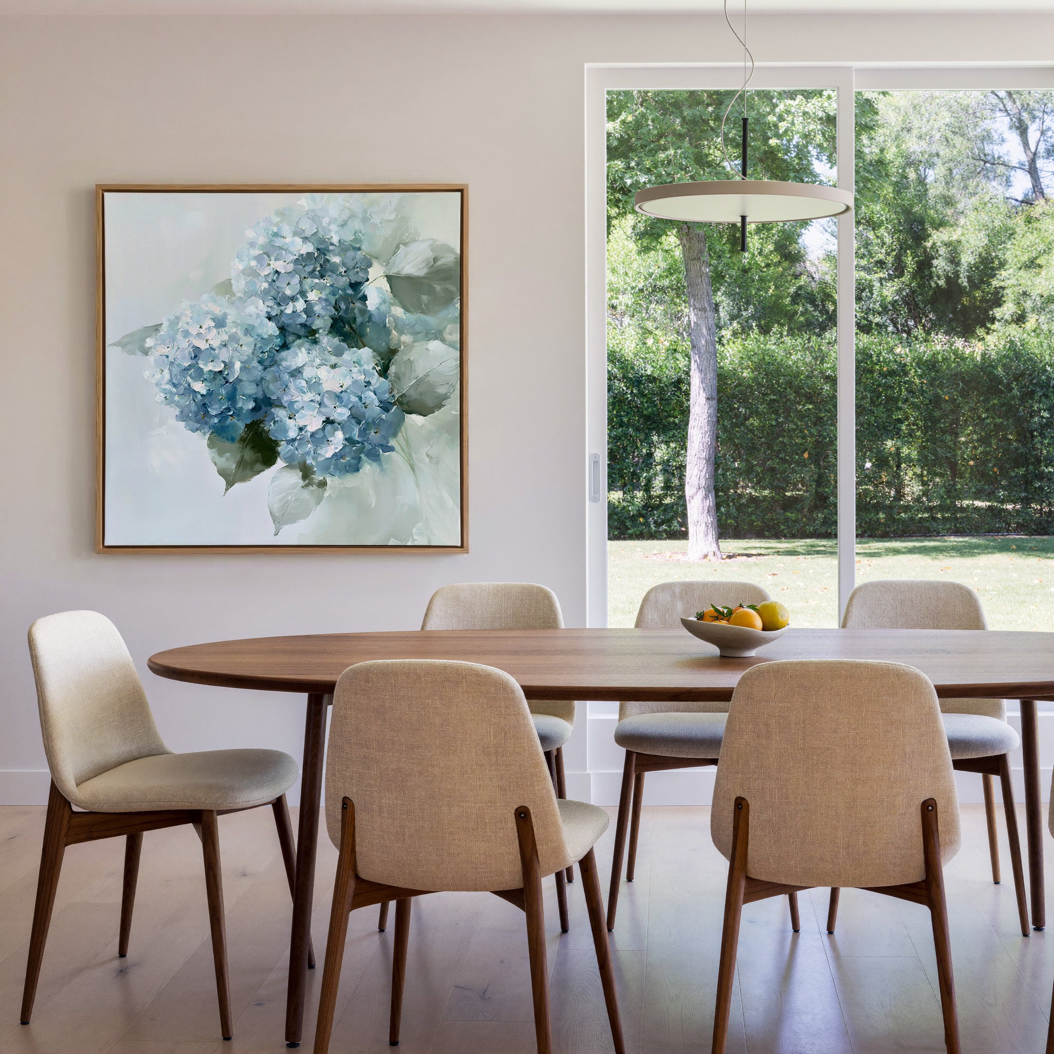 dusty blue hydrangea bouquet with pale green canvas wall art in an oak frame in a dining room