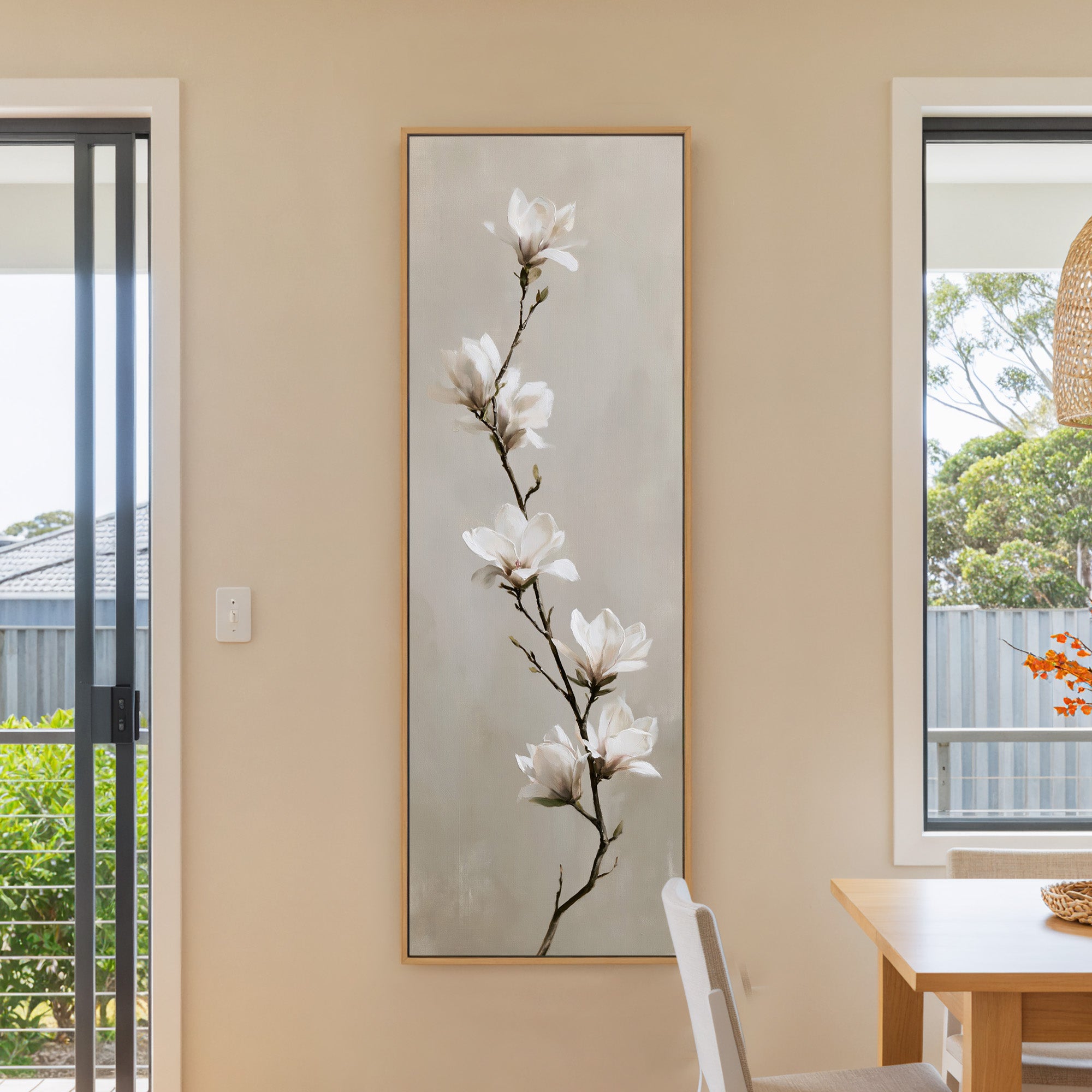 single white magnolia branch on a soft beige canvas wall art in a natural wood frame in a dining room