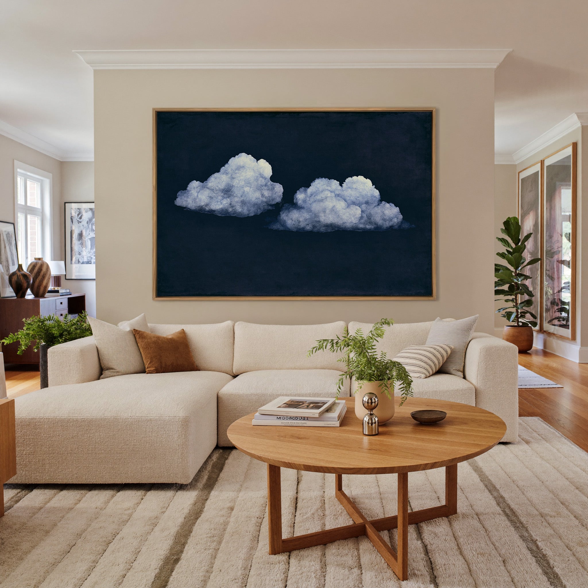 two pale clouds on a deep navy field canvas wall art in an oak frame in a living room