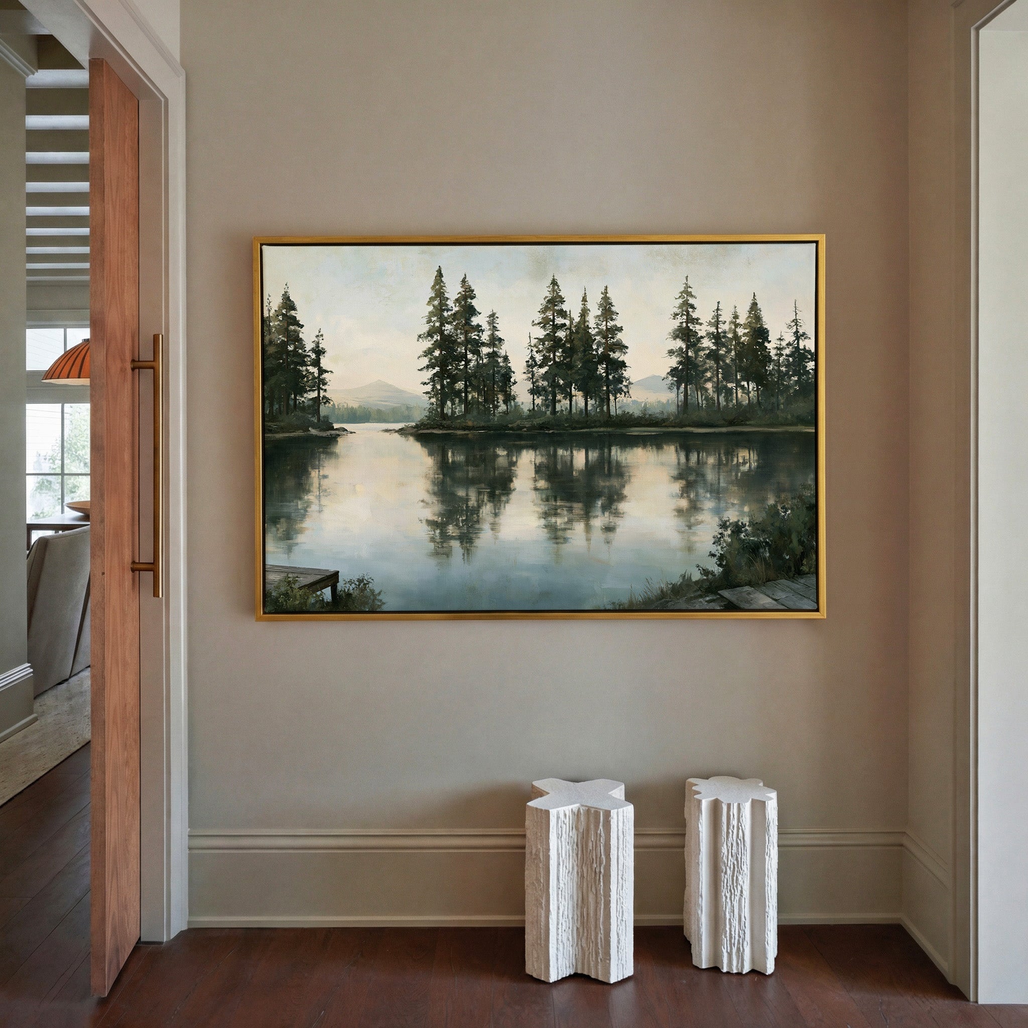 quiet lake with tall pines and pale distant canvas wall art in a gold frame in a styled room setting