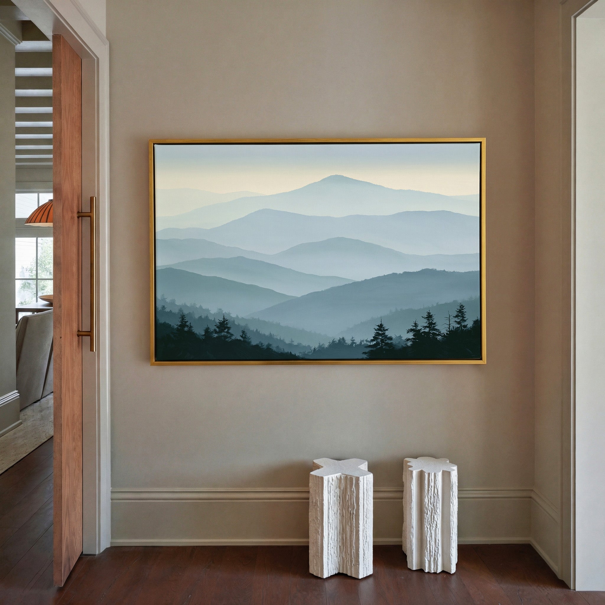 layered blue mountain ridges with mist and dark canvas wall art in a gold frame in a styled room setting