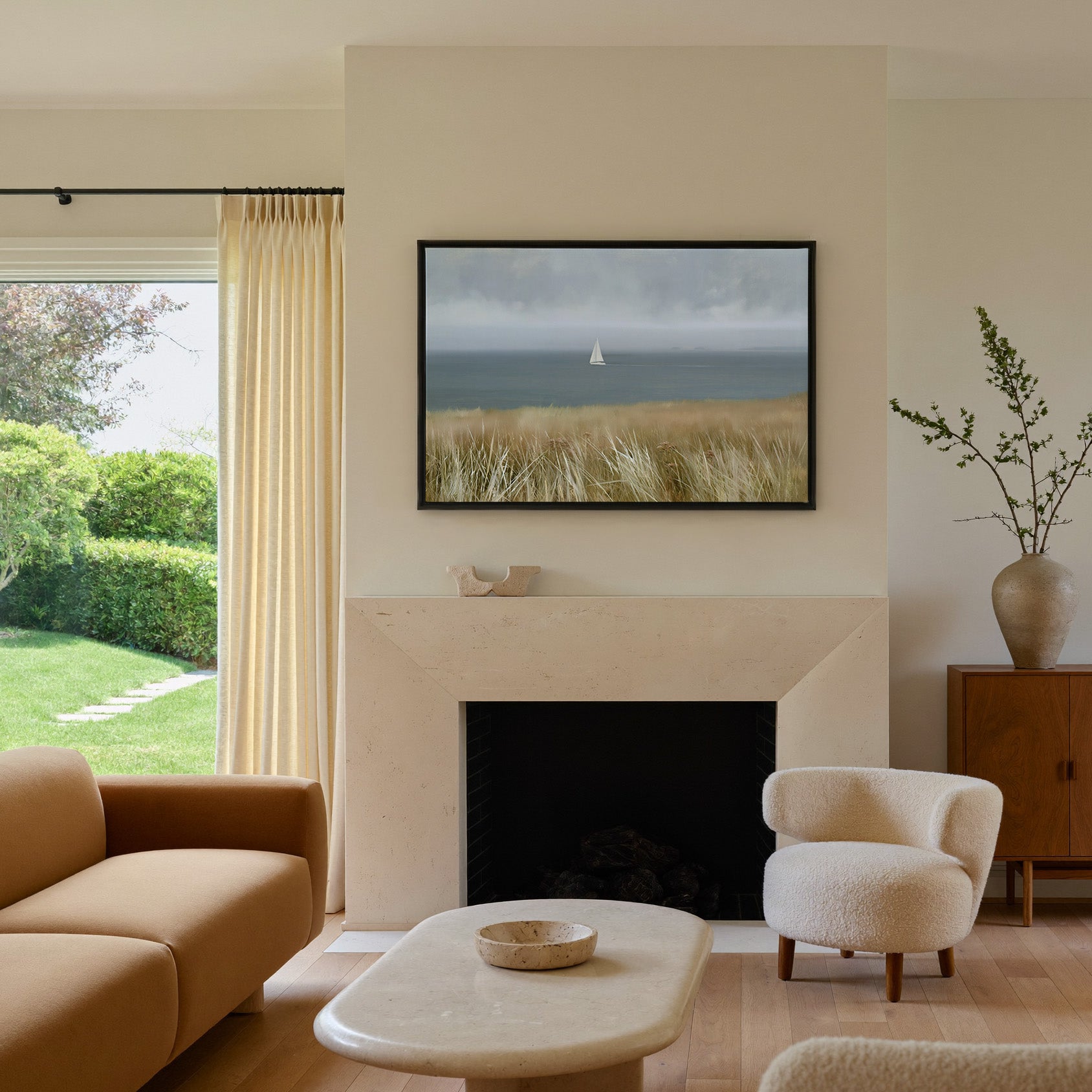 distant white sailboat on a gray blue sea canvas wall art in a black frame above a mantel