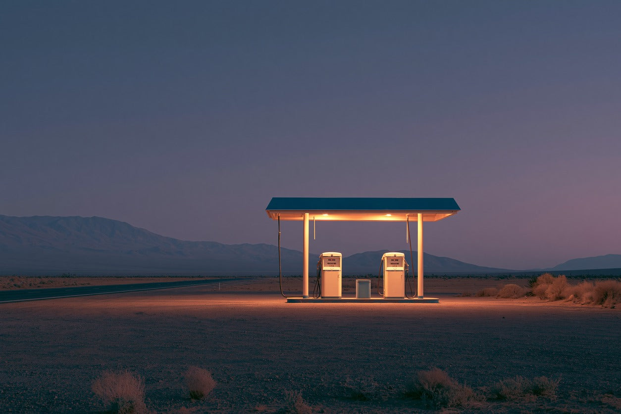 Lonely desert gas station under a blue dusk sky with warm lights and low mountains