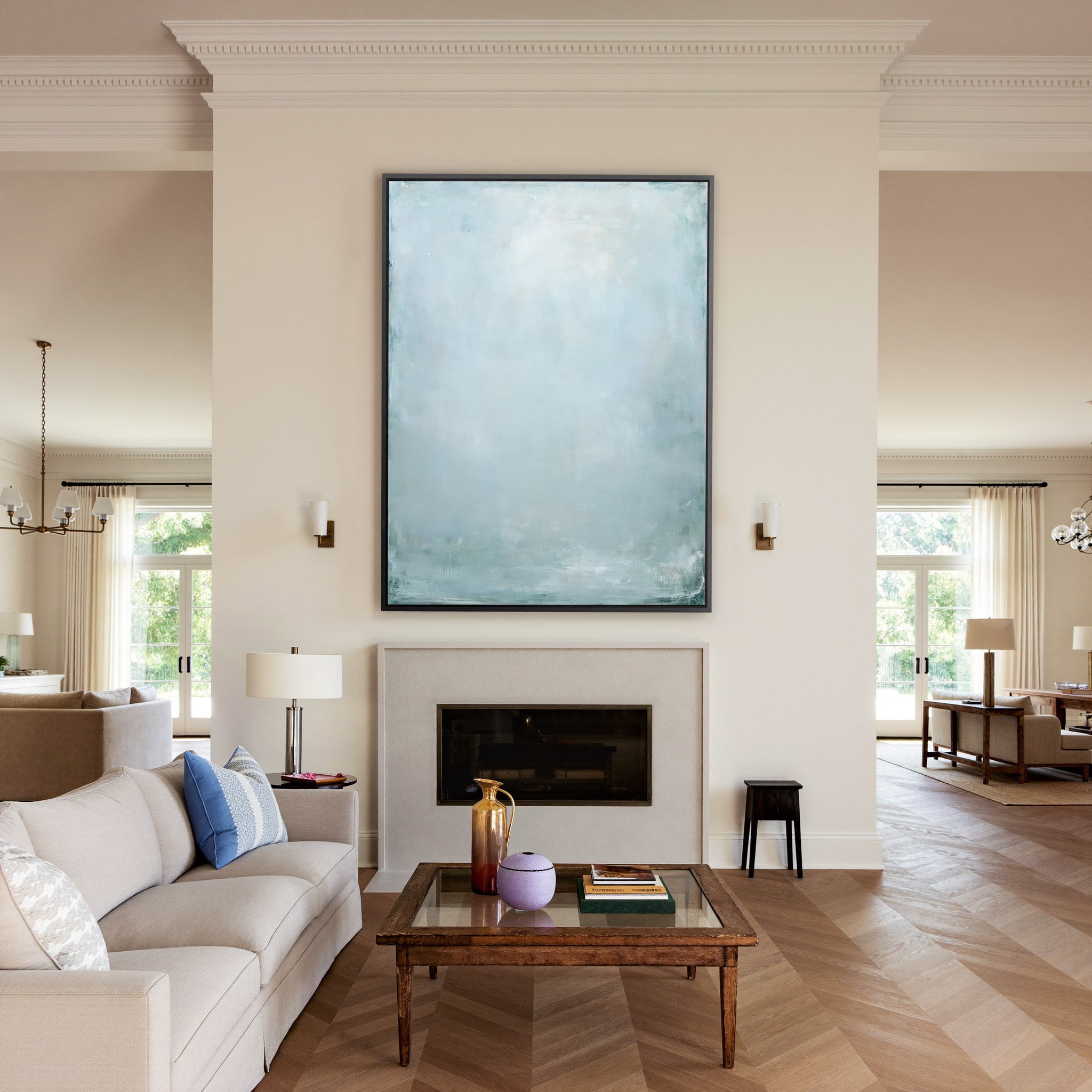 pale blue and white abstract with soft vertical canvas wall art in a black frame above a mantel