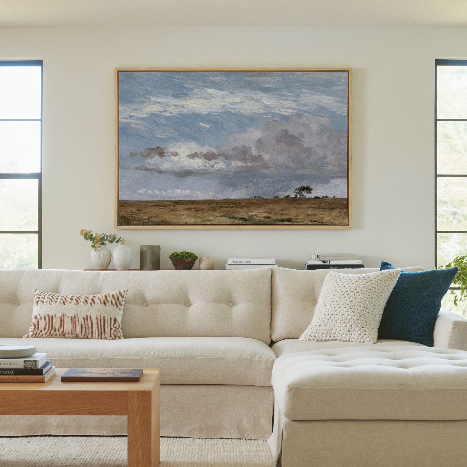 low field beneath immense rain clouds canvas wall art in a natural wood frame in a living room