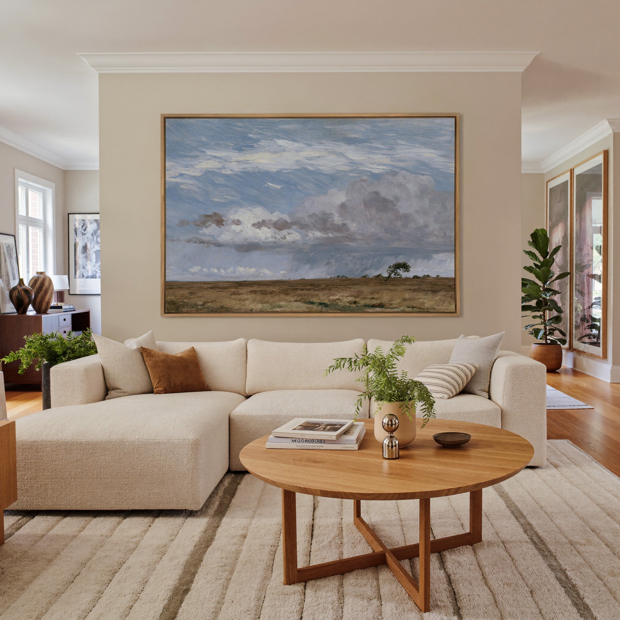 low field beneath immense rain clouds canvas wall art in an oak frame in a living room