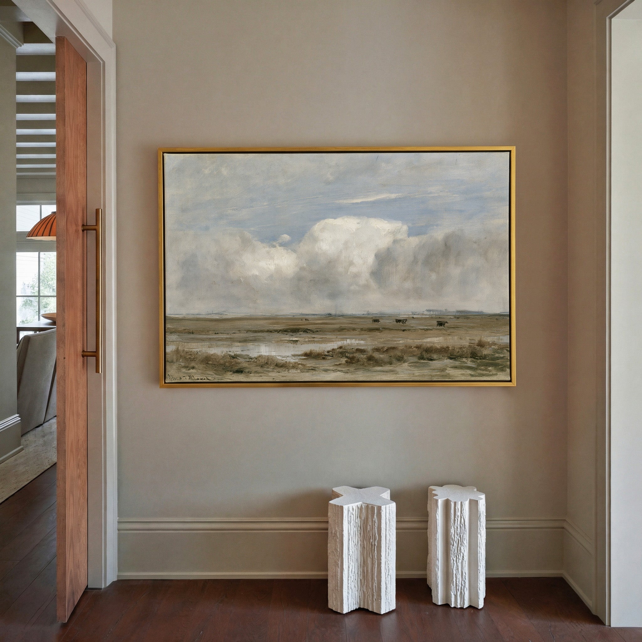 pale countryside with wet fields and a broad canvas wall art in a gold frame in a styled room setting