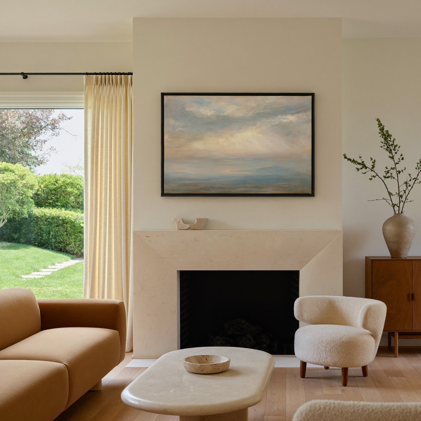 pale cloudscape with sea mist and a low distant canvas wall art in a black frame above a mantel