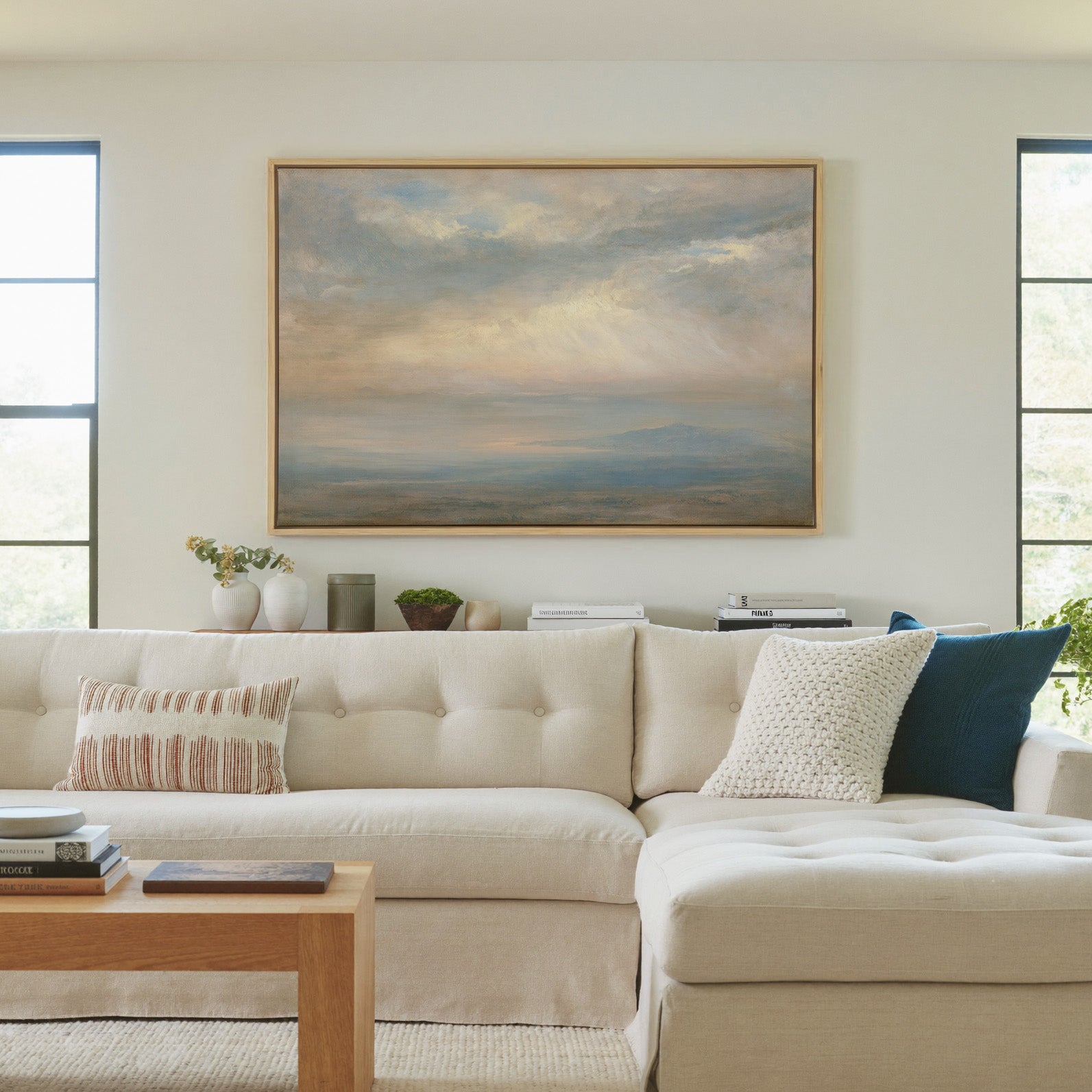 pale cloudscape with sea mist and a low distant canvas wall art in a natural wood frame in a living room