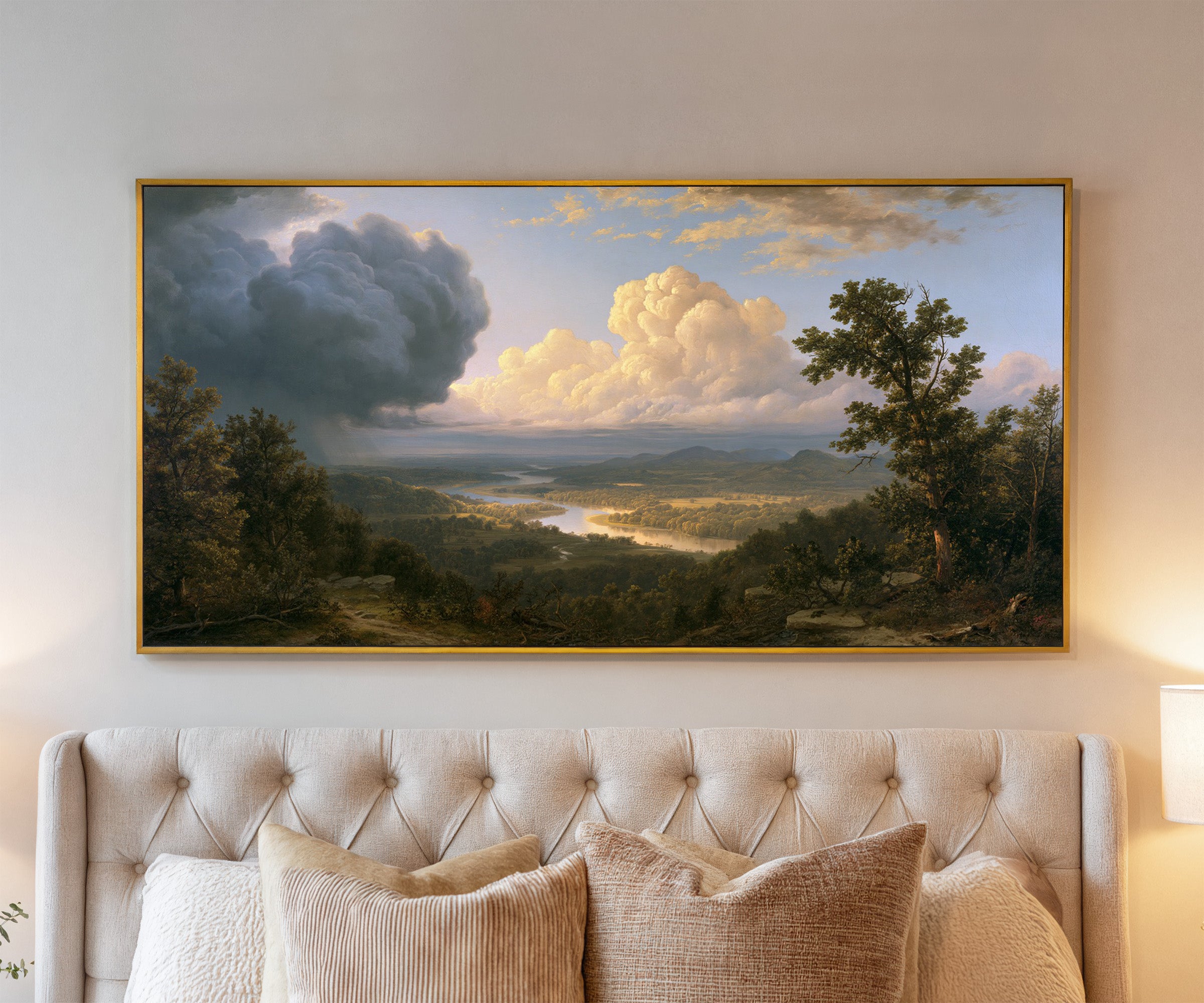 wide river valley with towering clouds canvas wall art in a gold frame above a bed