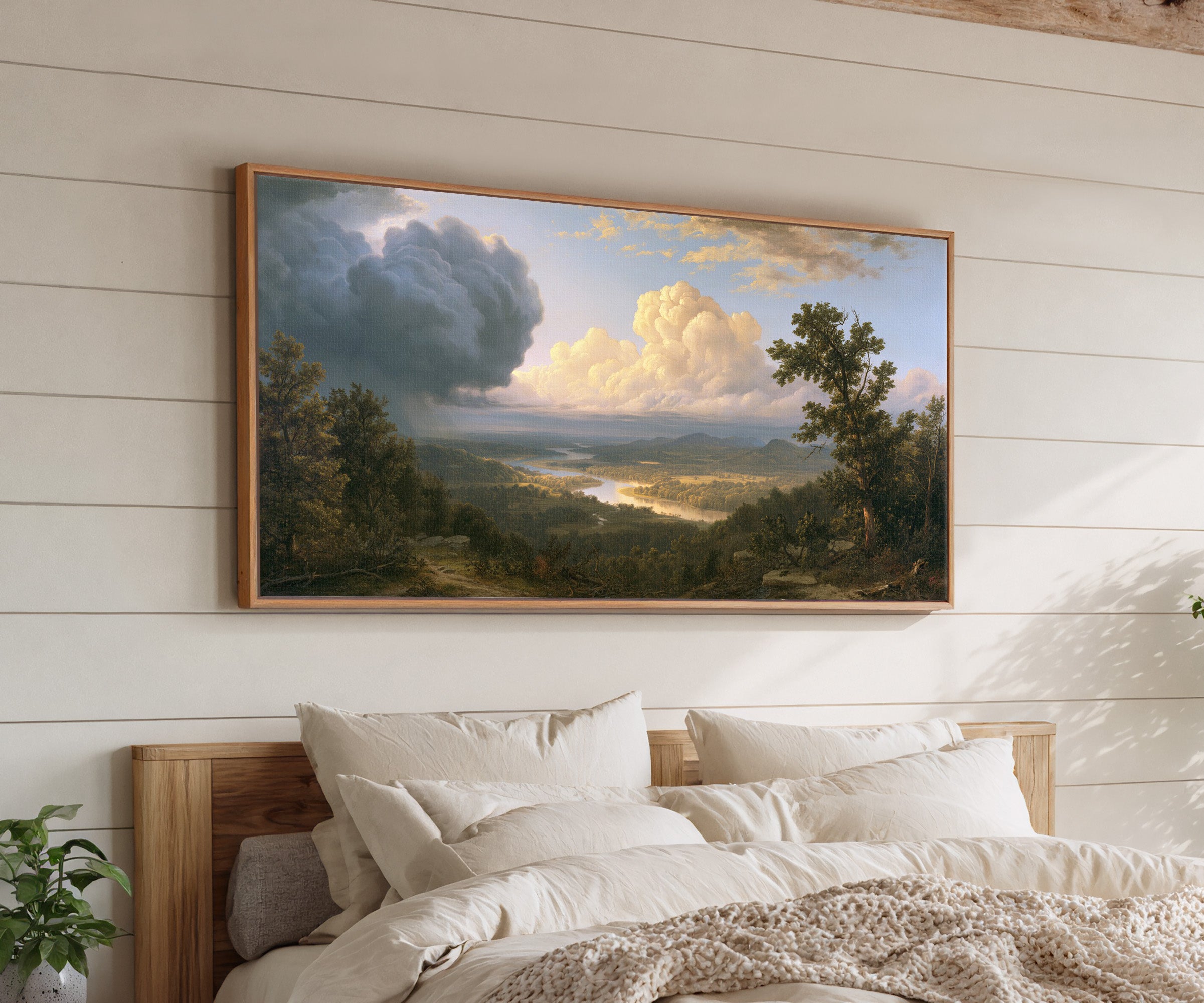 wide river valley with towering clouds canvas wall art in an oak frame above a bed