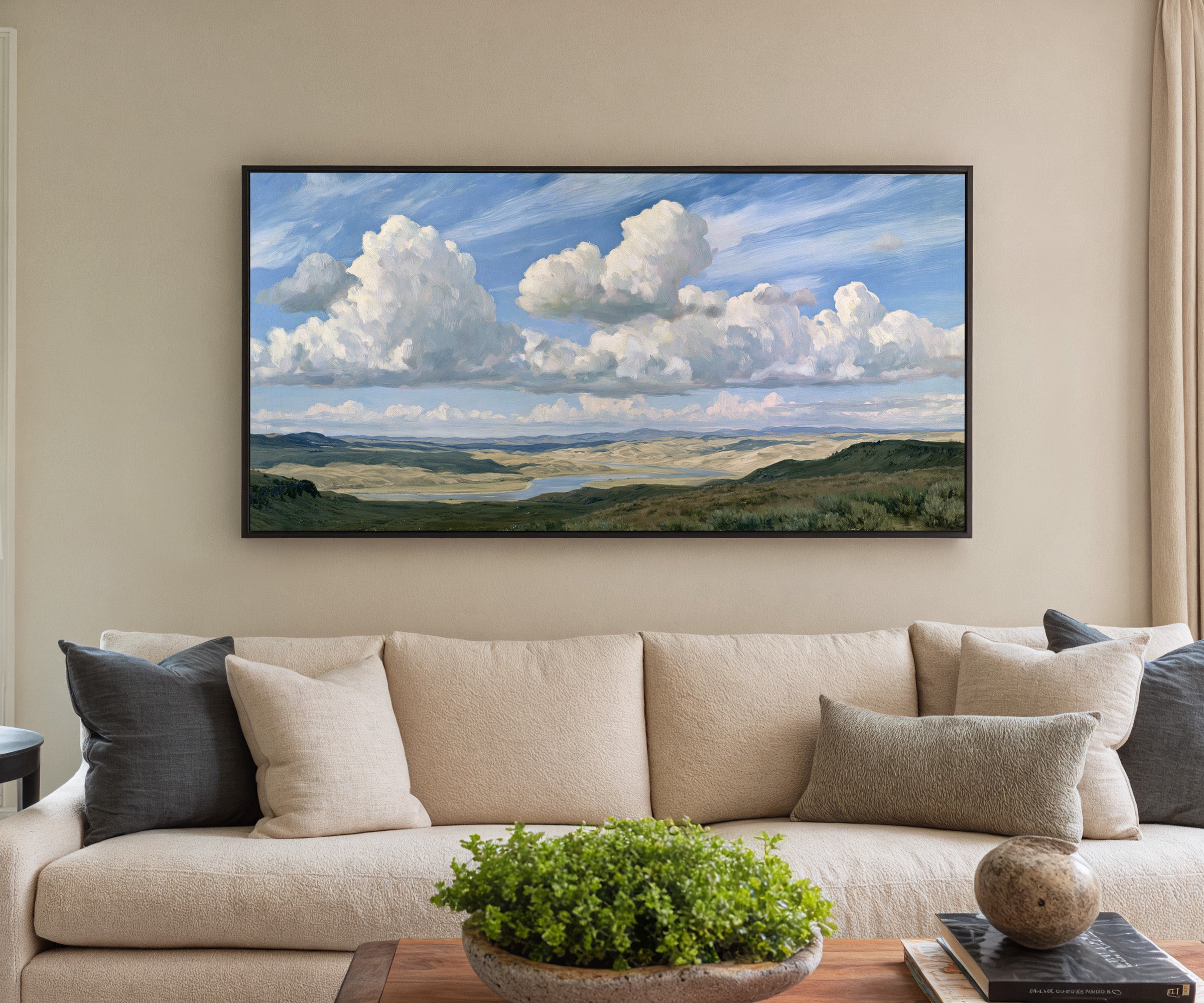blue sky with towering white cloud banks over a canvas wall art in a black frame in a styled room setting