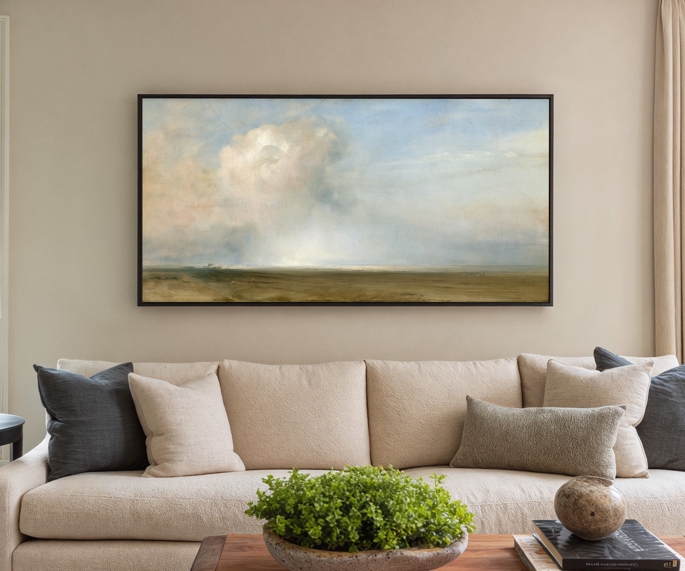 single towering cumulus cloud over a low plain canvas wall art in a black frame in a styled room setting
