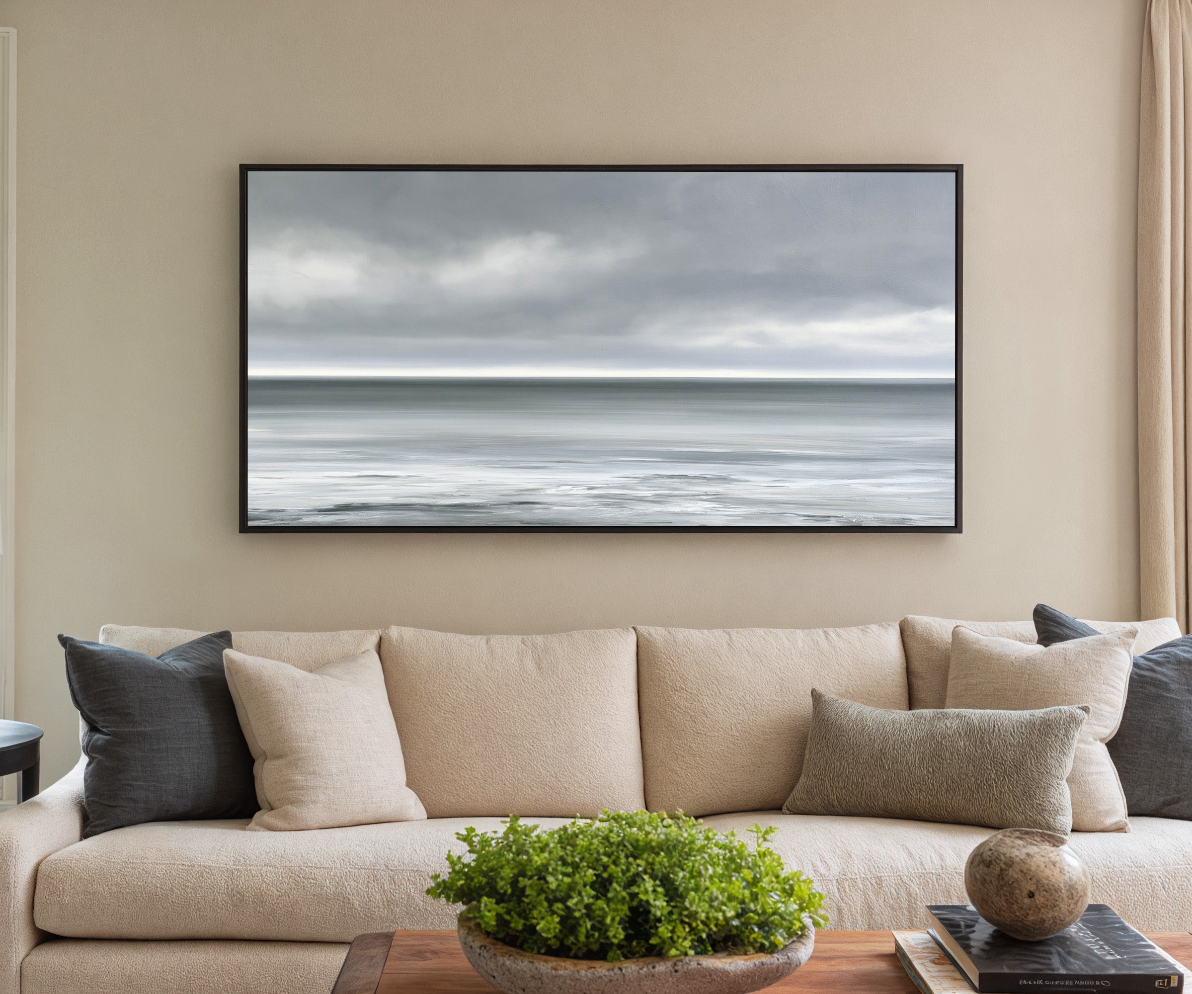 nearly monochrome sea beneath a smoke grey sky canvas wall art in a black frame in a styled room setting