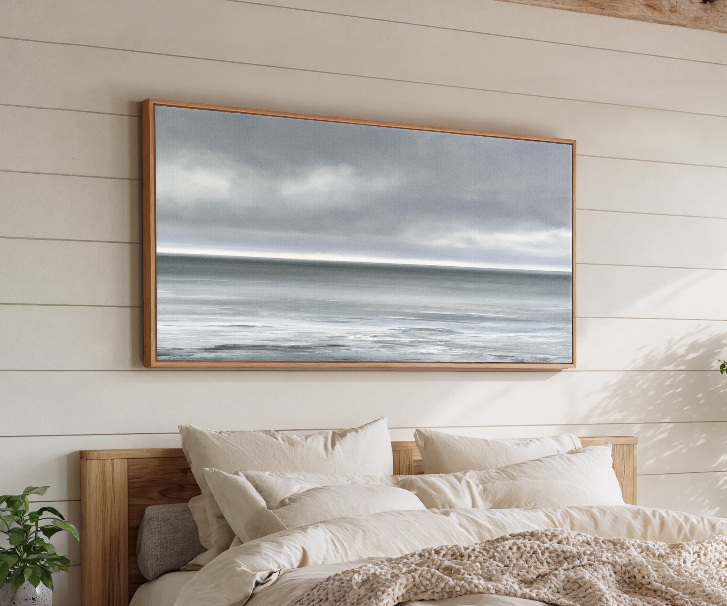 nearly monochrome sea beneath a smoke grey sky canvas wall art in an oak frame above a bed