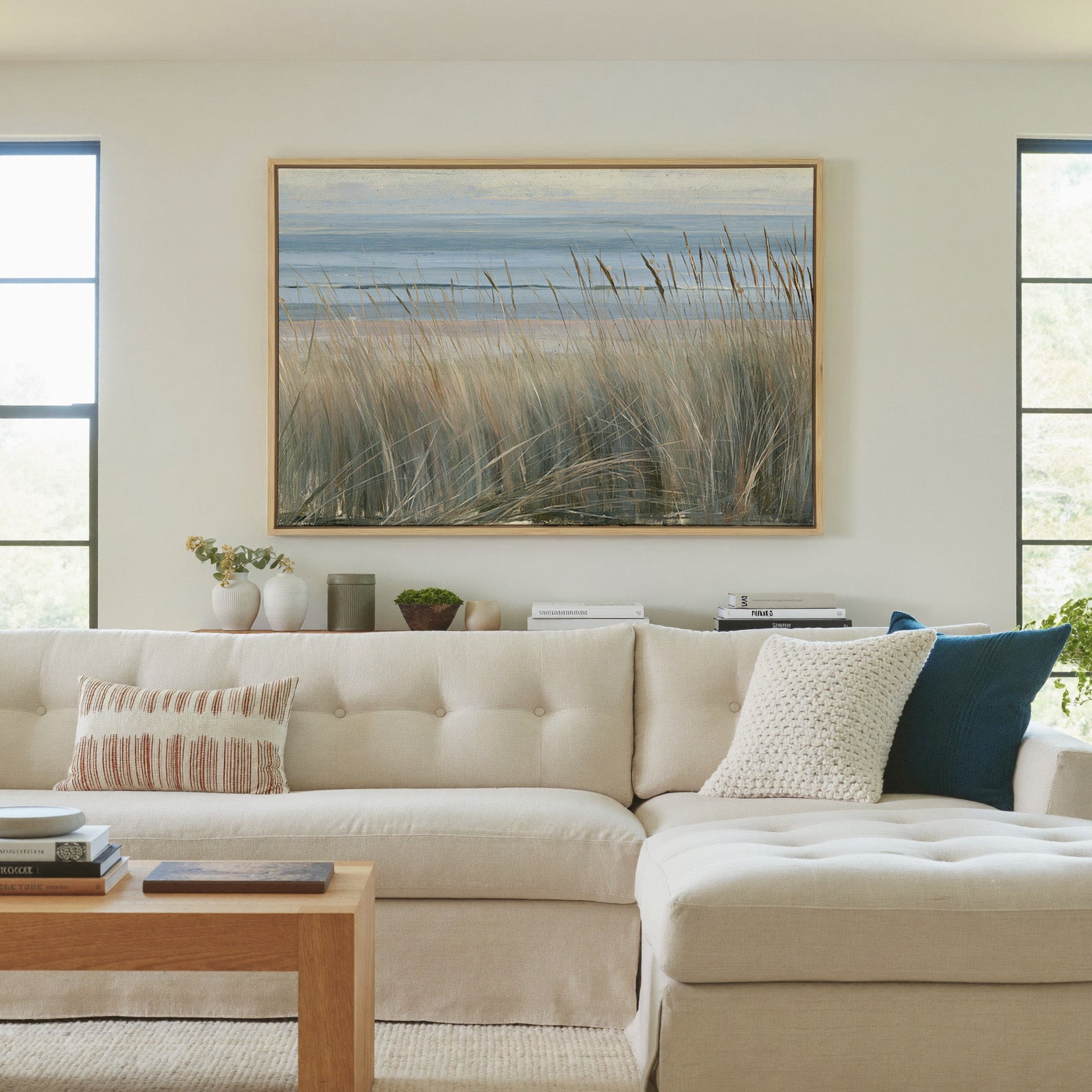 beach grass with blue water and pale dune bands canvas wall art in a natural wood frame in a living room
