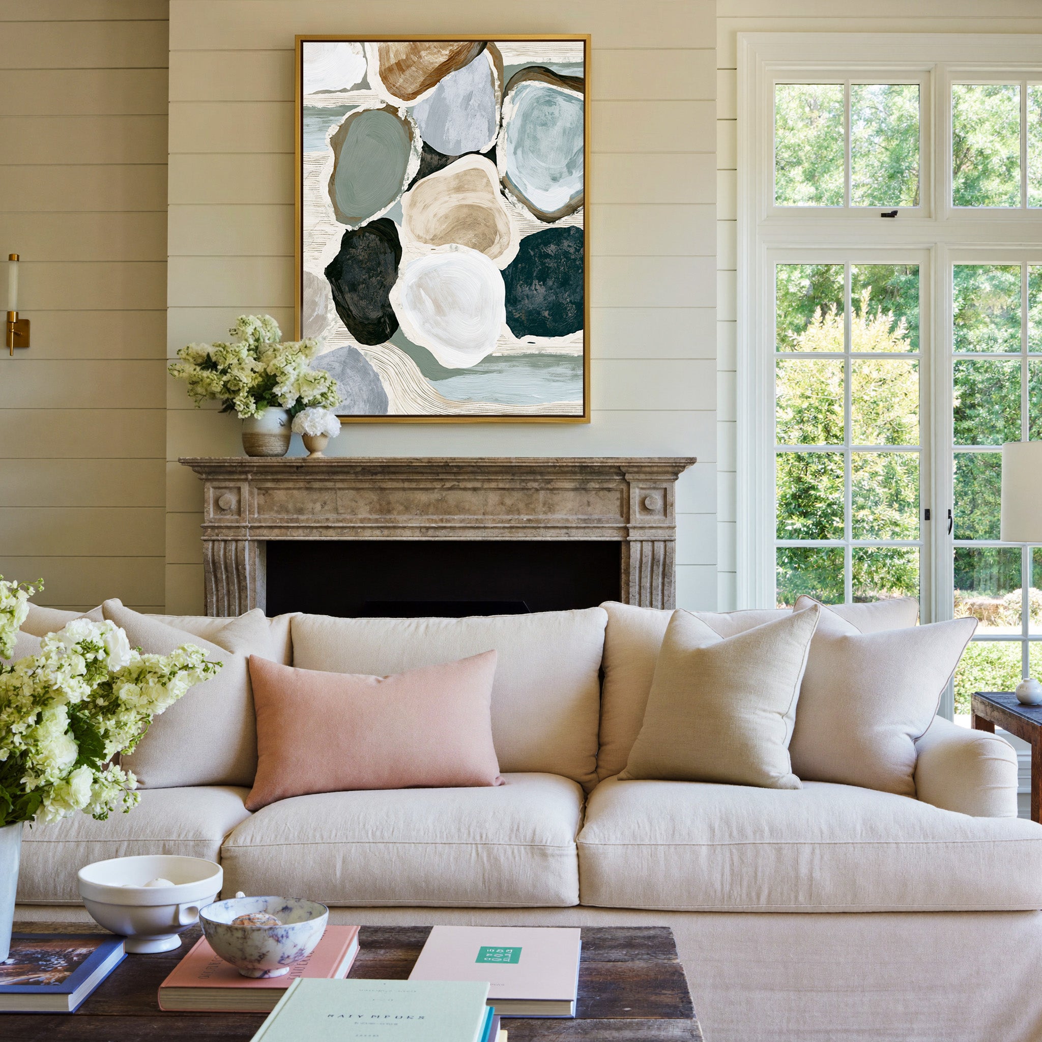 muted coastal abstract with oyster shell shapes canvas wall art in a gold frame above a mantel