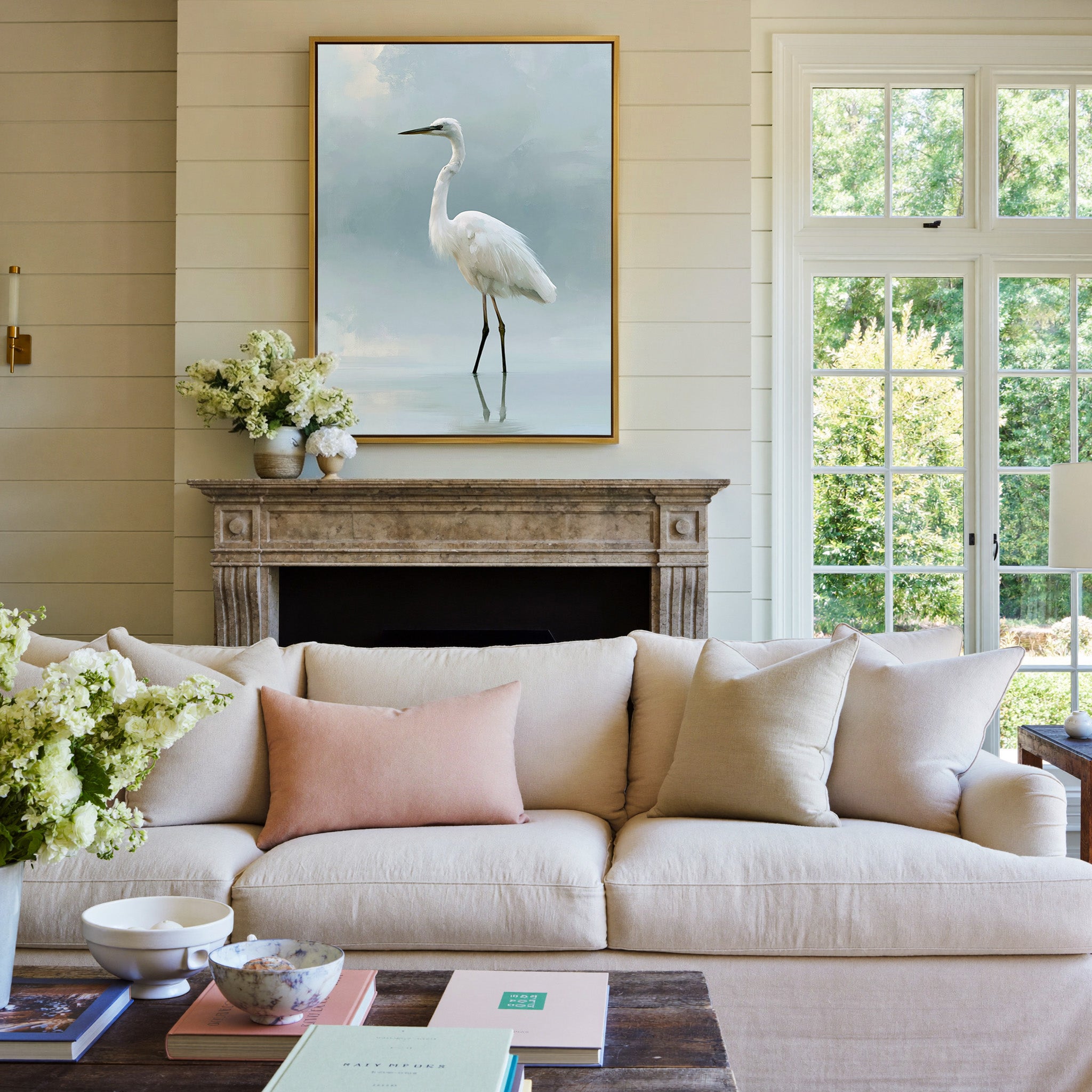 white heron standing in pale reflective water canvas wall art in a gold frame above a mantel