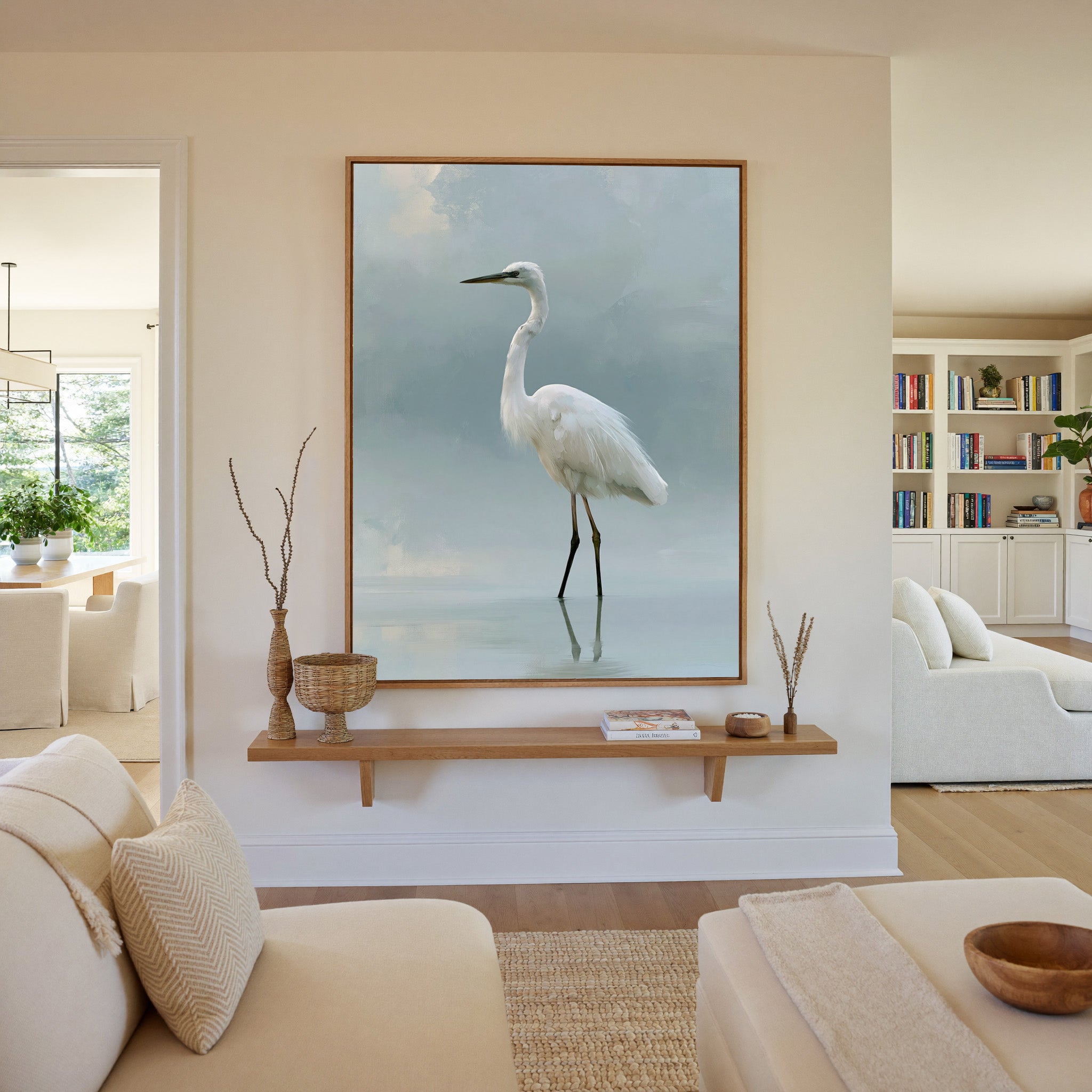 white heron standing in pale reflective water canvas wall art in an oak frame in a living room