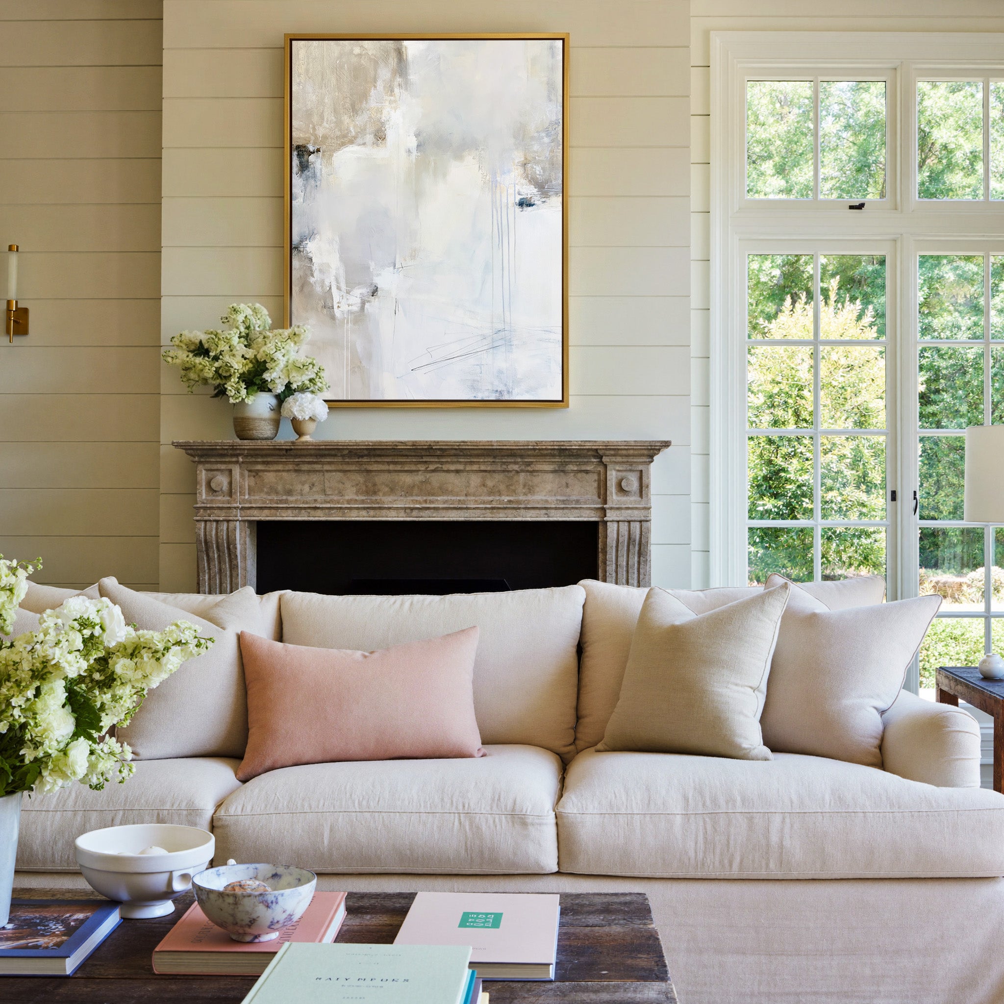 soft white and beige abstract with pale blue canvas wall art in a gold frame above a mantel