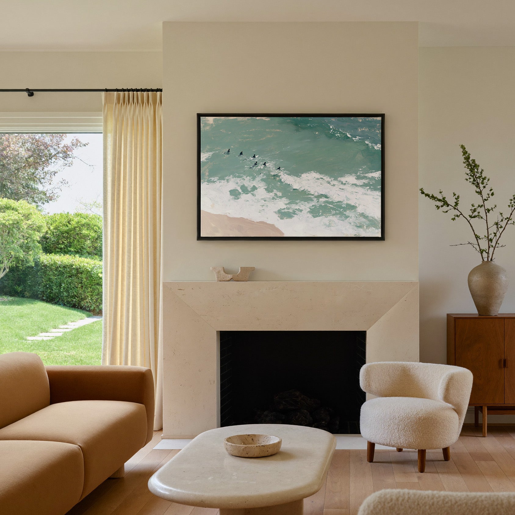 turquoise surf with small figures beyond the canvas wall art in a black frame above a mantel
