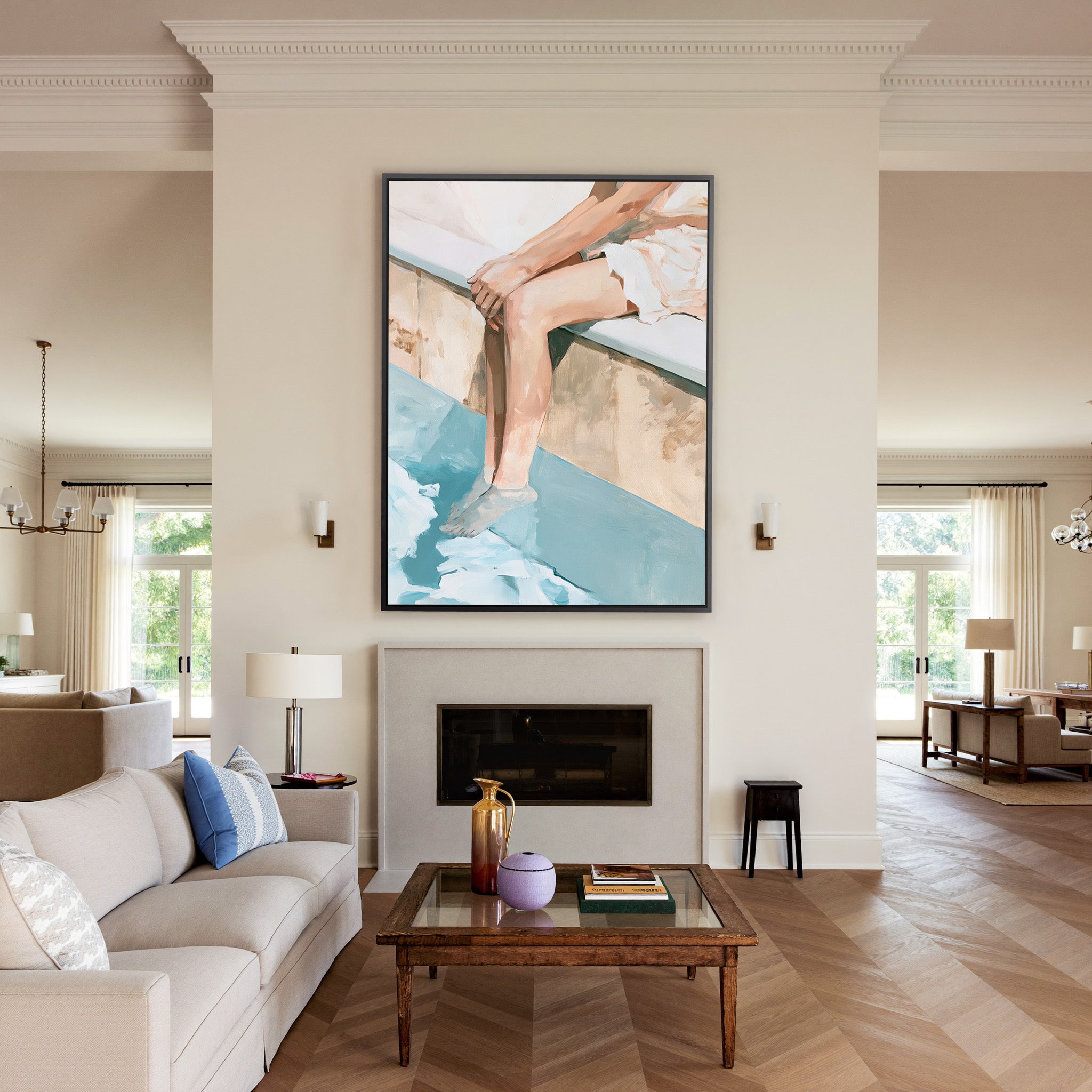cropped seated figure with bent legs and blue canvas wall art in a black frame above a mantel