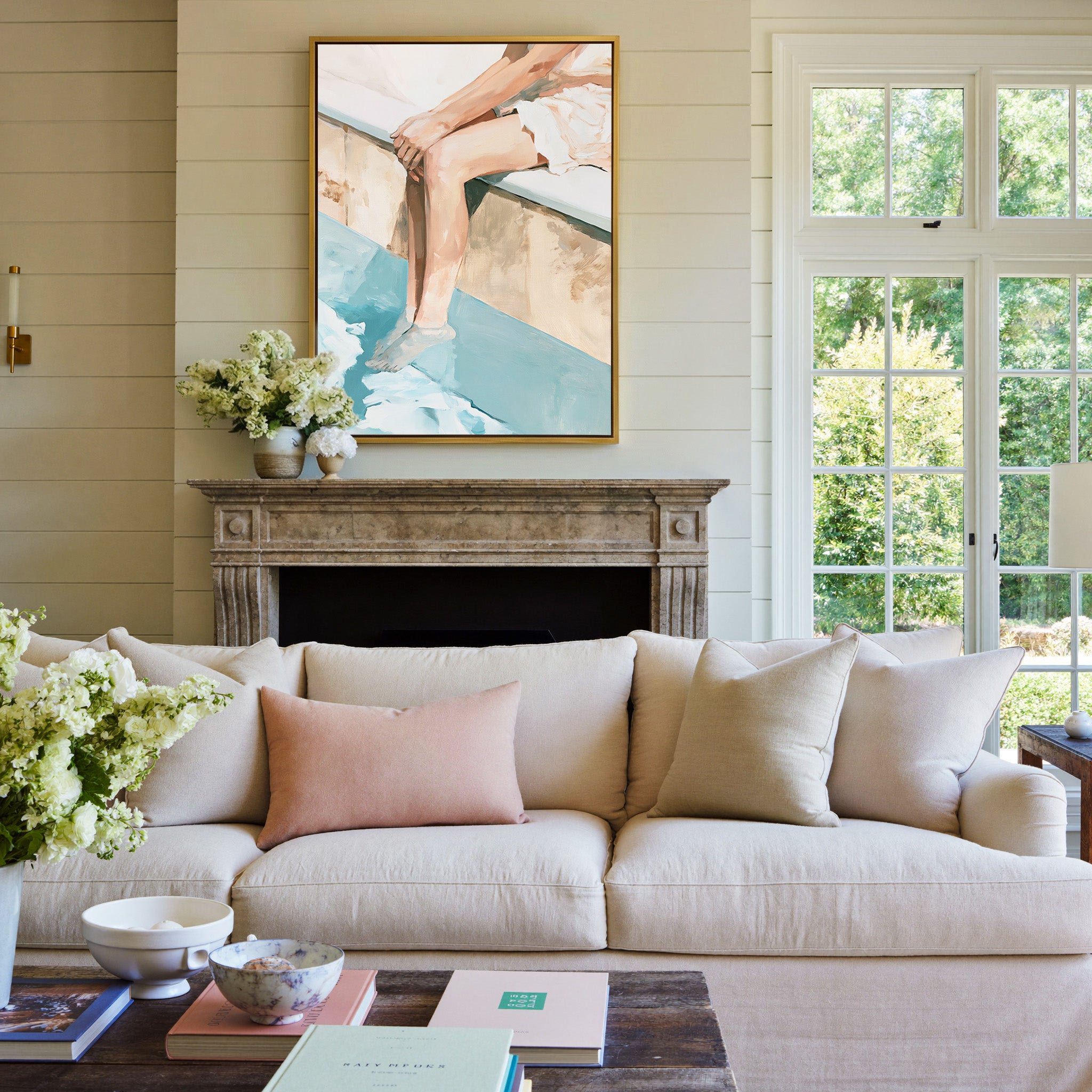 cropped seated figure with bent legs and blue canvas wall art in a gold frame above a mantel