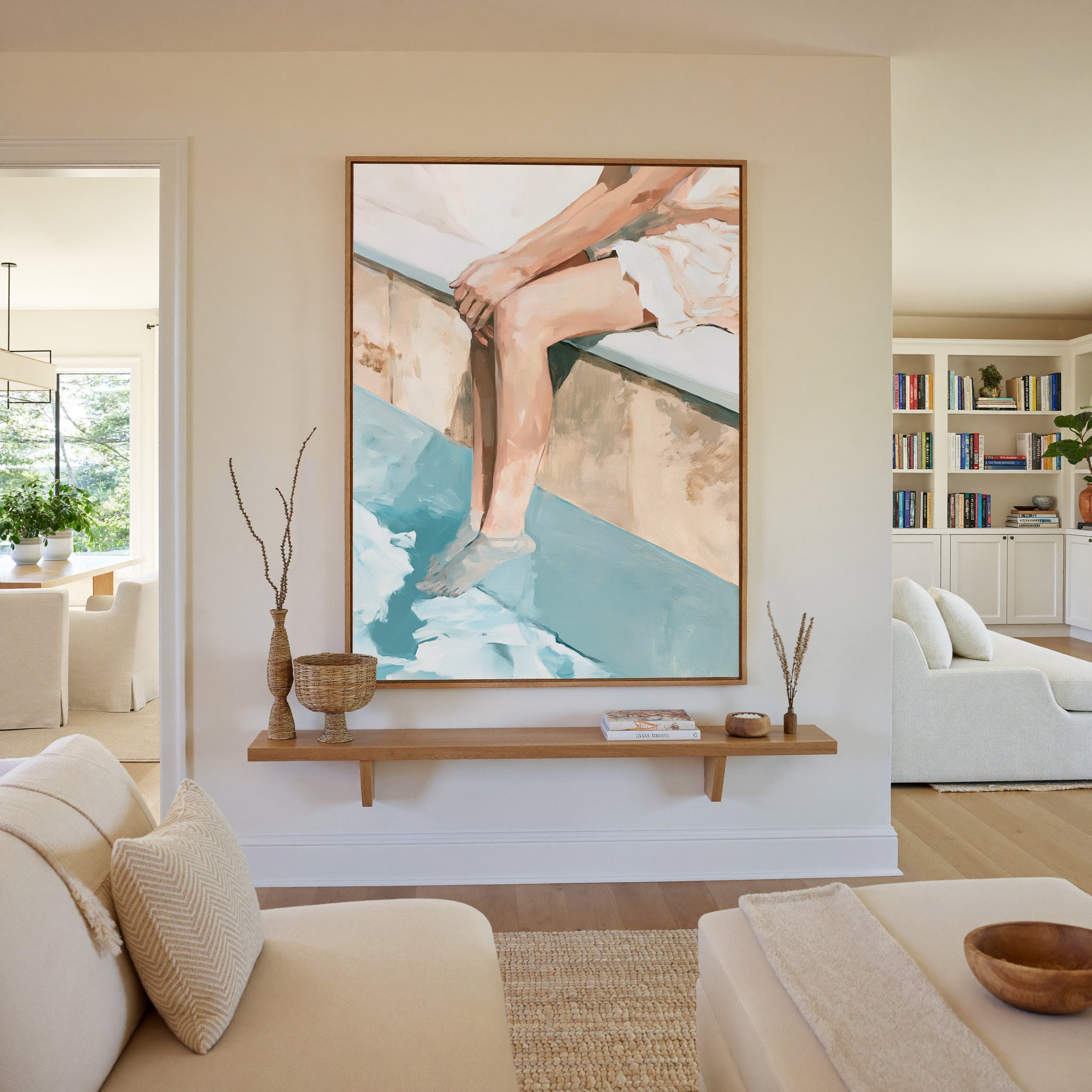 cropped seated figure with bent legs and blue canvas wall art in an oak frame in a living room